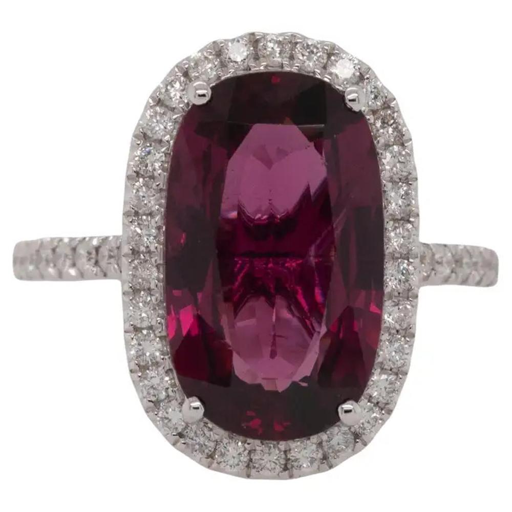 Dieser atemberaubende Ring aus 18 Karat Weißgold präsentiert einen faszinierenden Rhodolith-Granat von 6,26 Karat im Ovalschliff, der einen satten, tiefroten Farbton hat, der Wärme und Raffinesse ausstrahlt. Den Mittelstein akzentuieren 0,61 Karat