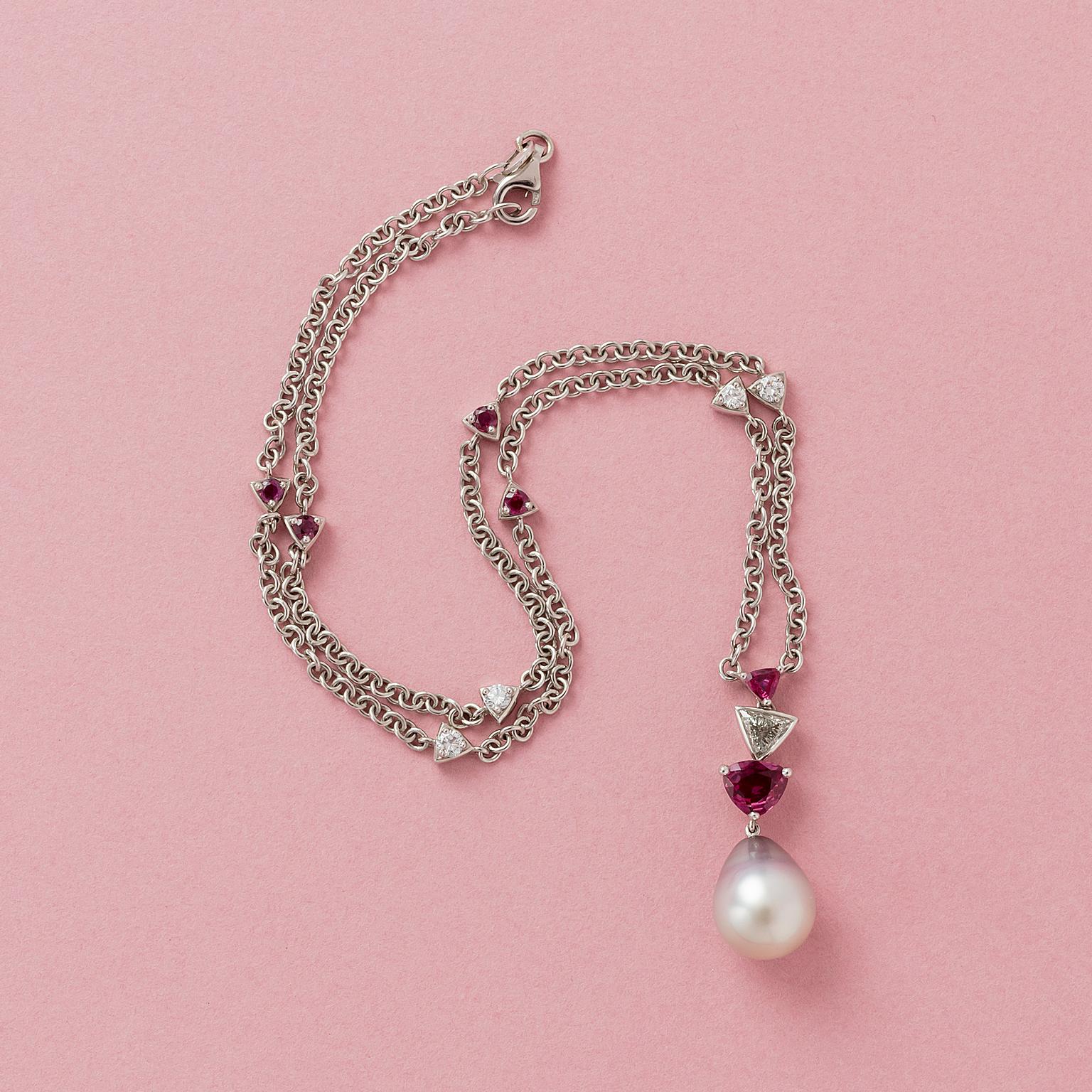 An 18 carat white gold chain and pendant with a light grey Tahiti pearl above which a trilliant cut ruby (1.05 carat) and a trilliant cut diamond (0.4 carat I, P) and a trilliant cut ruby (0.9 carat) on a white gold chain that is decorated with four
