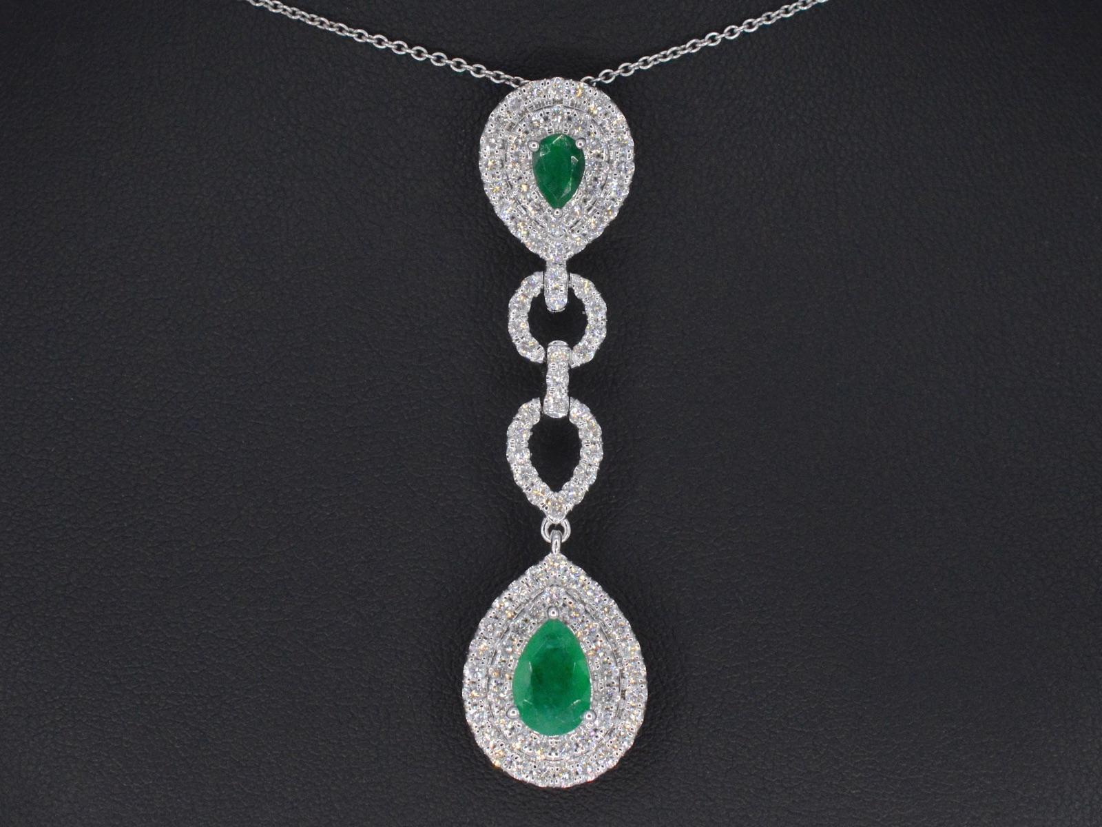 This gold pendant is a true statement piece that exudes luxury and sophistication. It features a stunning design that showcases brilliant-cut diamonds and two droplet-shaped emeralds, adding a pop of color to the piece. The diamonds and emeralds are