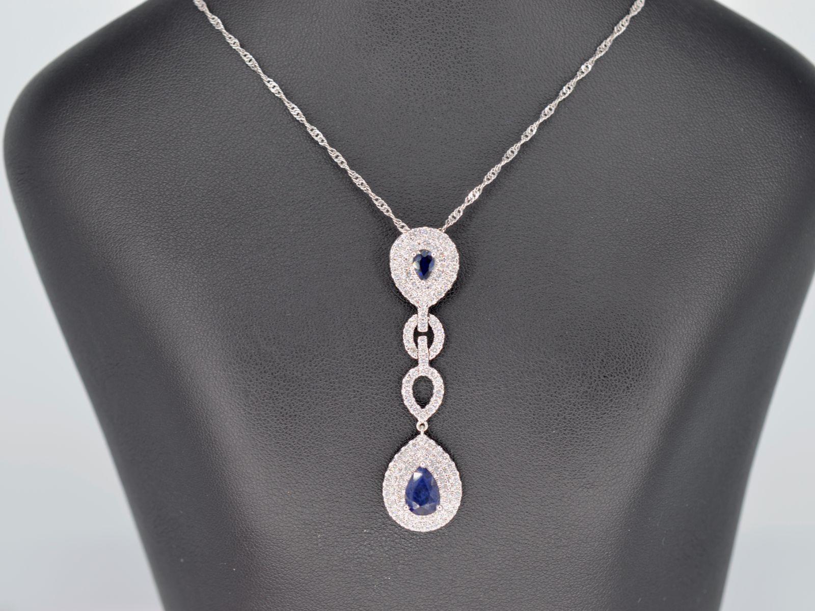 This white gold pendant is an elegant and luxurious piece of jewelry, featuring a long design and adorned with exquisite Swiss cut diamonds and pear-shaped sapphires. The white gold is a premium quality metal that is highly lustrous and durable. The