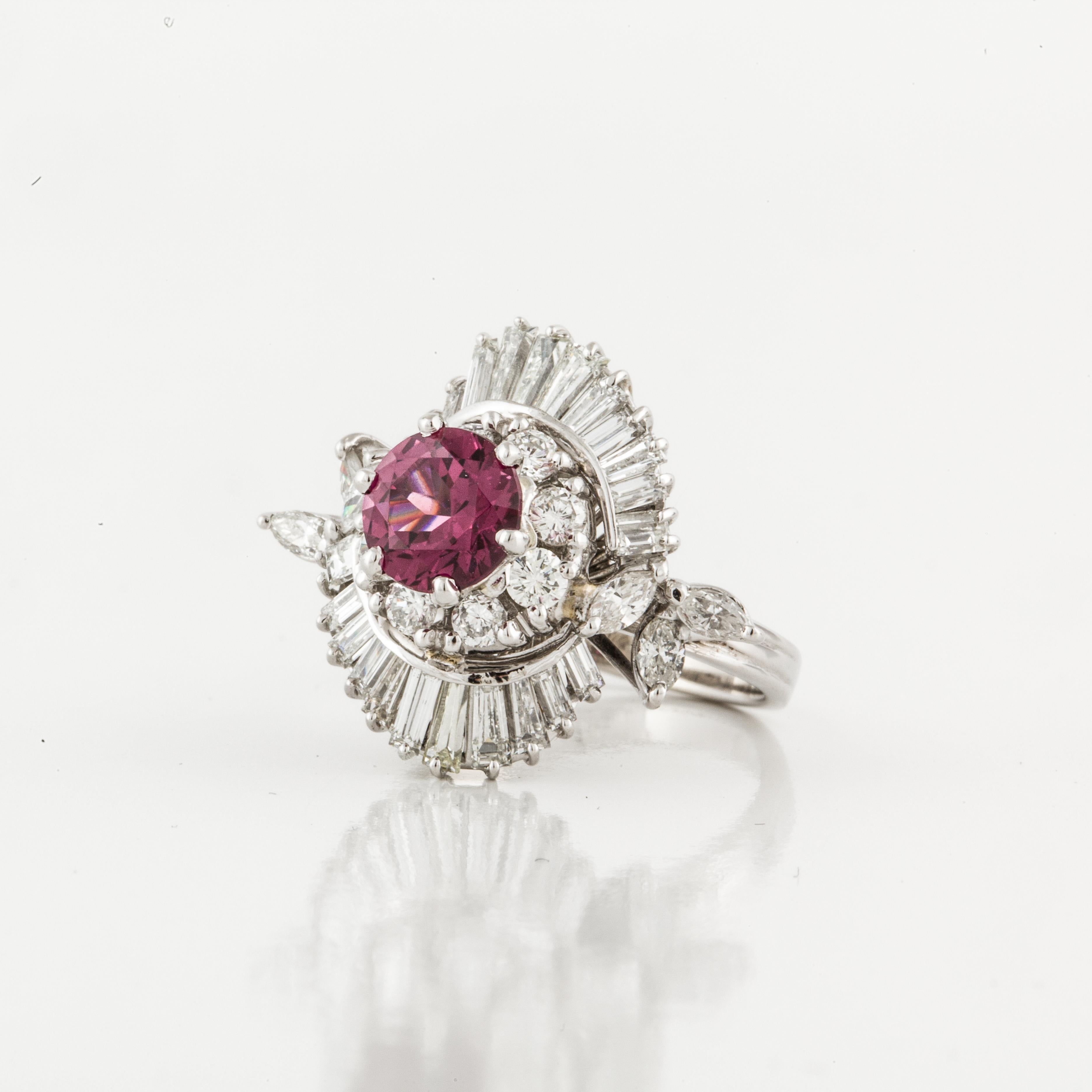 14K white gold cocktail ring featuring a round rhodolite garnet surrounded by round, baguette and marquise diamonds.  Total diamond weight is 1.30 carats.  The presentation area measures 1 inch by 7/8 inches and stands 1/2 inch off the finger.