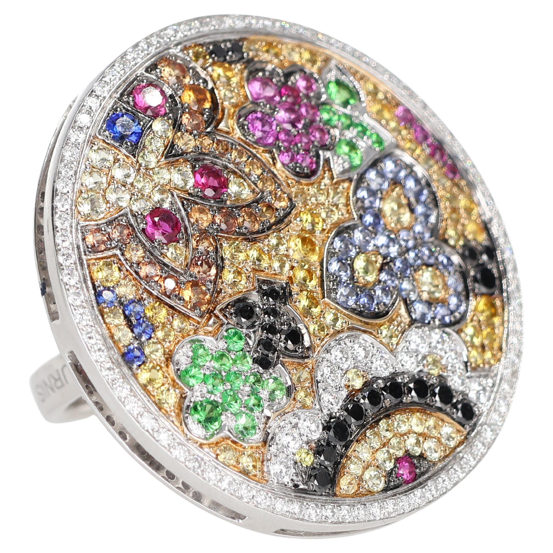 A sophisticated transformable ring featuring a detachable pendant adorned with an intricate floral motif set in precious stones. White diamonds, rubies, blue and yellow sapphires create a vibrant mosaic, blending elegance with artistic flair. A