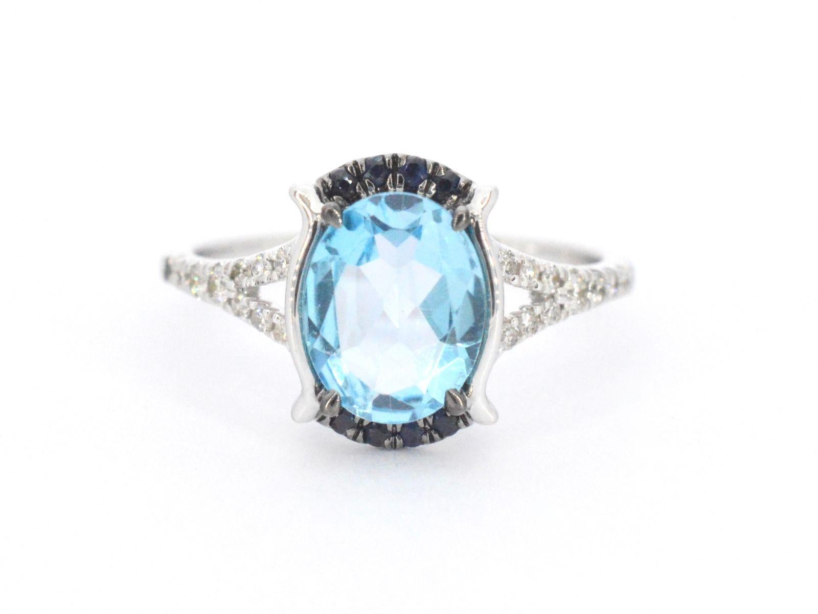 This stunning white gold design ring features a gorgeous topaz gemstone and a vibrant sapphire, accented by dazzling diamonds. The design of the ring is unique and eye-catching, with a modern and sophisticated feel. The diamonds are expertly placed