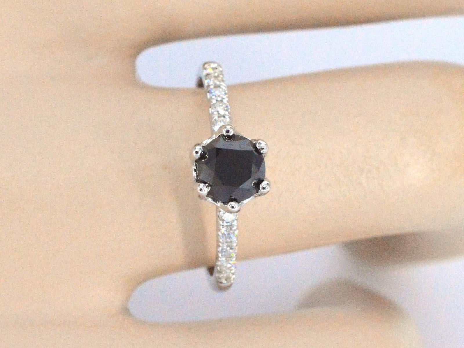 This white gold ring is a stunning and unique piece of jewelry featuring one brilliant cut black diamond and several white diamonds. The white gold is a premium quality metal that is highly lustrous and durable. The black diamond is carefully