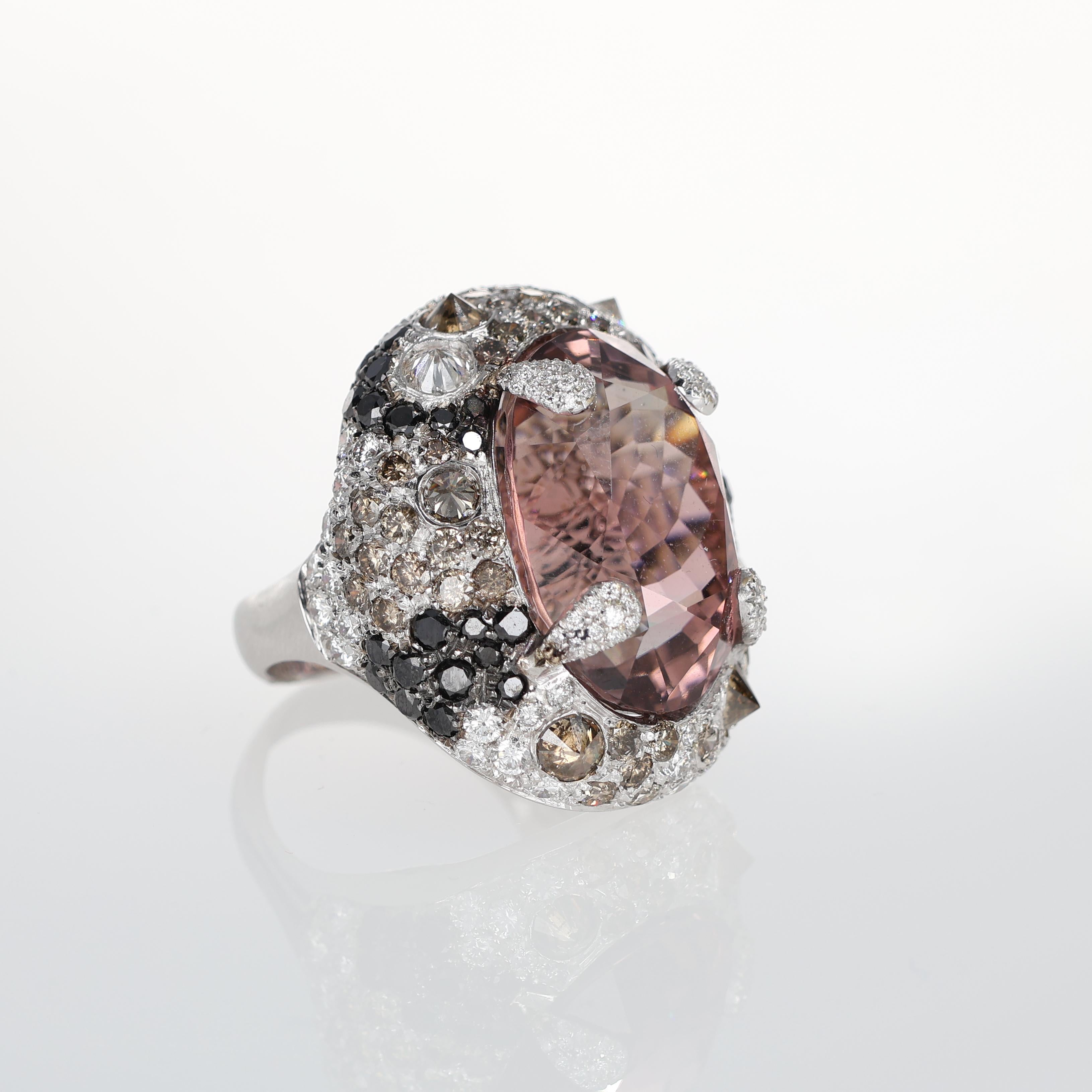 
An exceptional statement ring crafted in 18kt white gold, featuring a striking oval-cut topaz secured by four pavé-set diamond prongs. The setting is adorned with a luxurious mix of natural white, brown, and black diamonds, creating a sophisticated