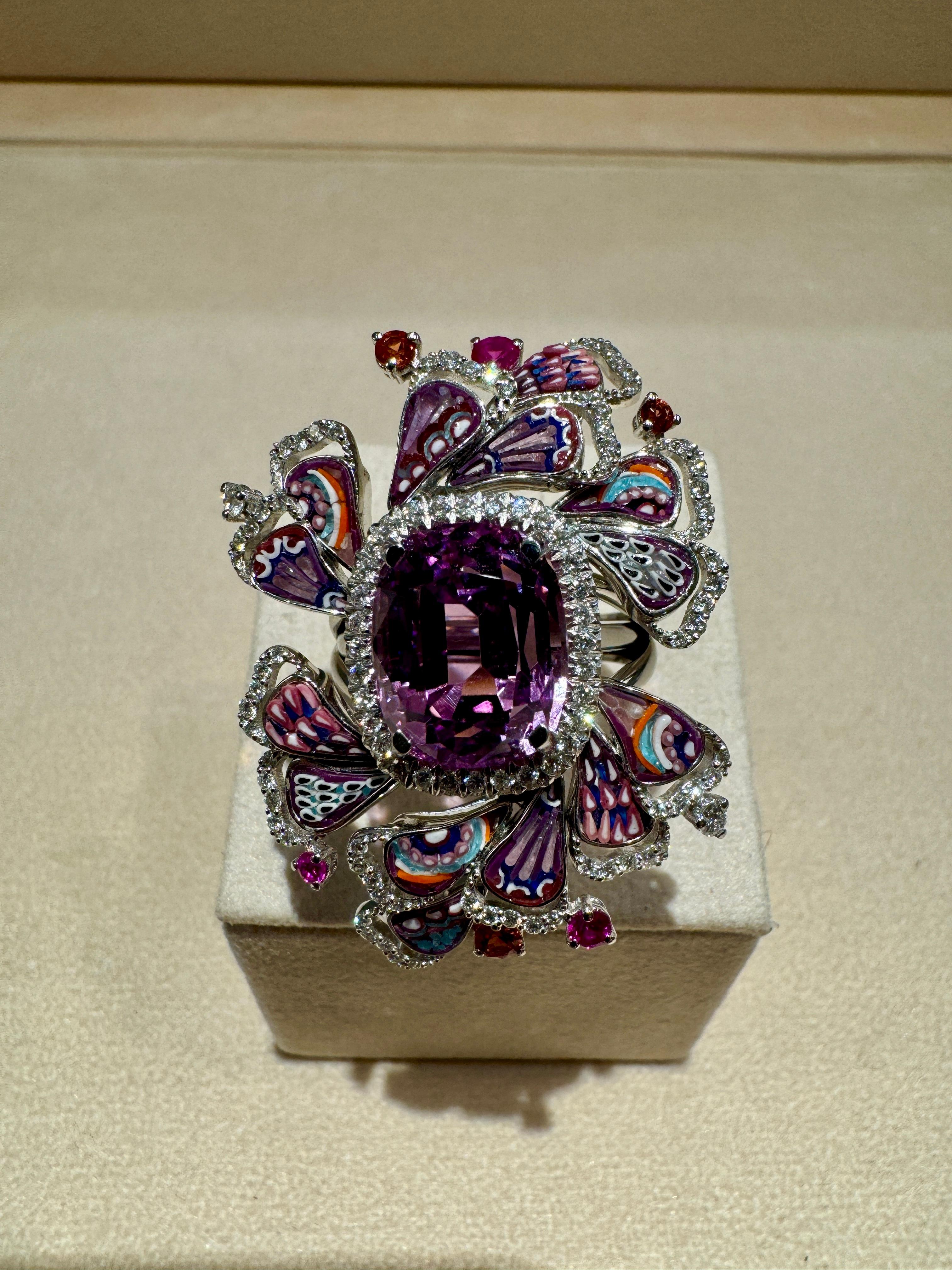 The Dewdrop Flamingo ring is a radiating purple masterpiece. 
At the heart of the ring is a magnificent Kunzite stone that is accompanied buy a beautiful micromosaic skirt. 
The micromosaic patterns are intricately made with vibrant hues of purple,