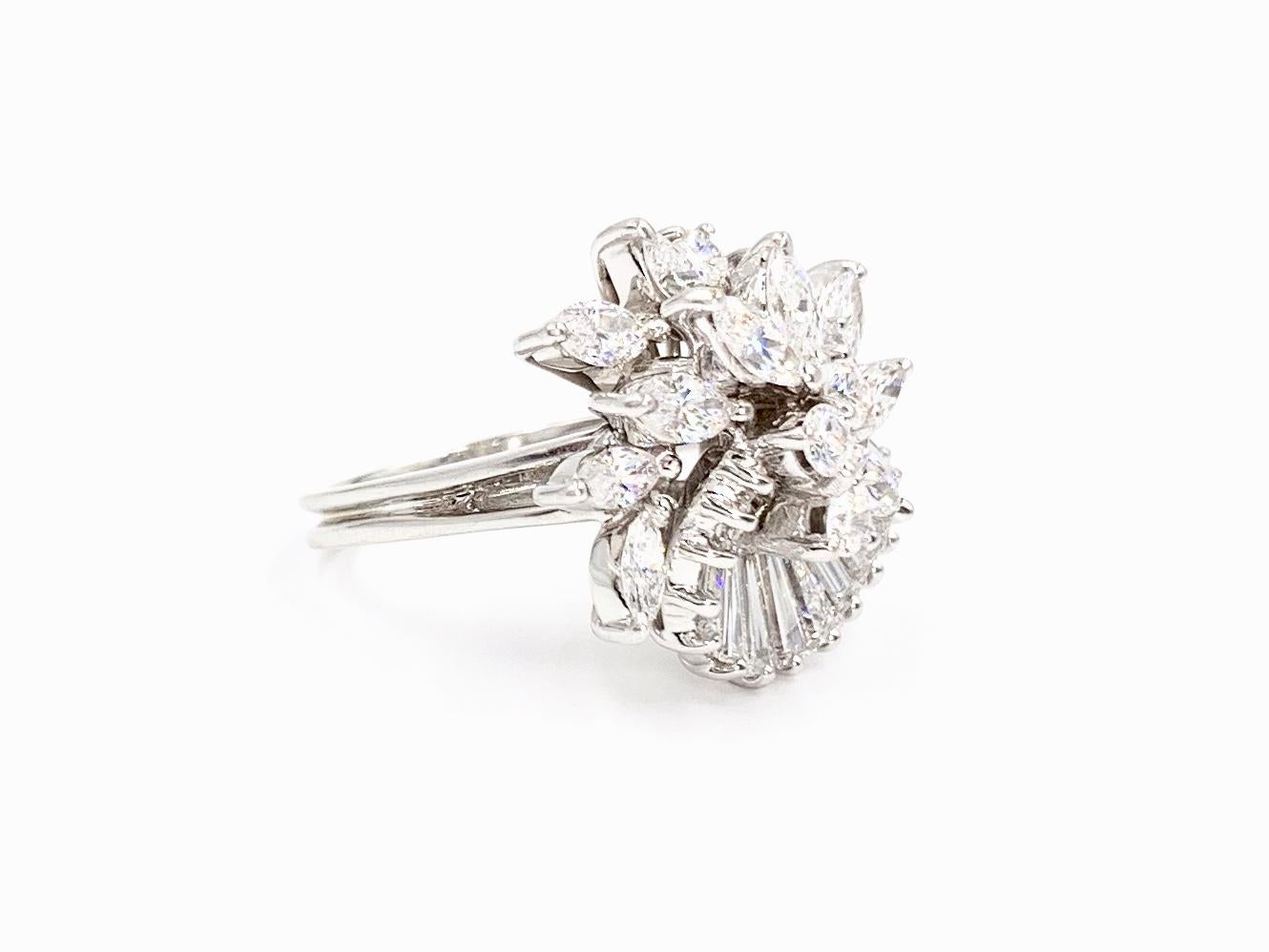 A feminine and dynamic 14 karat white gold round brilliant, marquise and baguette cut diamond spray ring. Unique ring has a soft curvy shape, reminiscent of a flower with the marquise diamonds as petals. Ring consists of 15 baguettes, 10 marquise