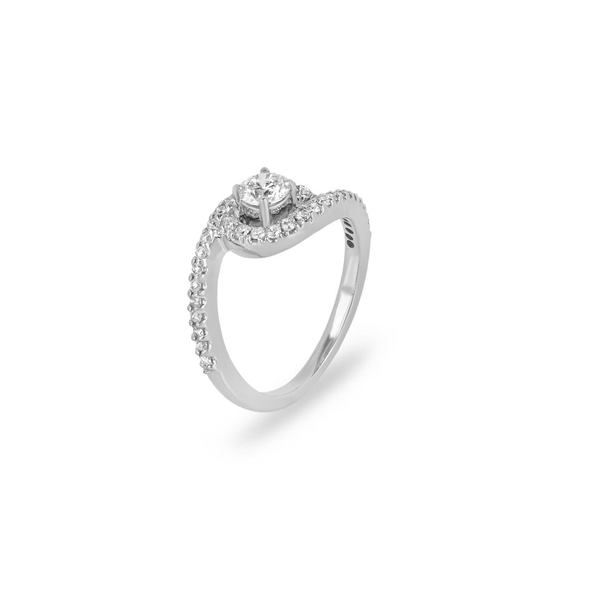 A contemporary 18k white gold diamond ring. The ring is set to the centre with a round brilliant cut diamond weighing 0.32ct,  I colour and VS2 clarity. The diamond is further complimented by pave set round brilliant cut diamond shoulders with an
