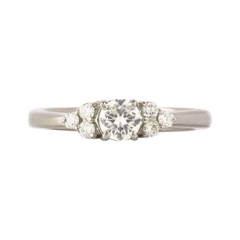 An elegant 18k white gold diamond dress ring. The ring is set to the centre with a round brilliant brilliant cut diamond weighing 0.33ct, colour H and VS clarity set within a classic 4 claw setting. Complementing the centre stone are 3 round