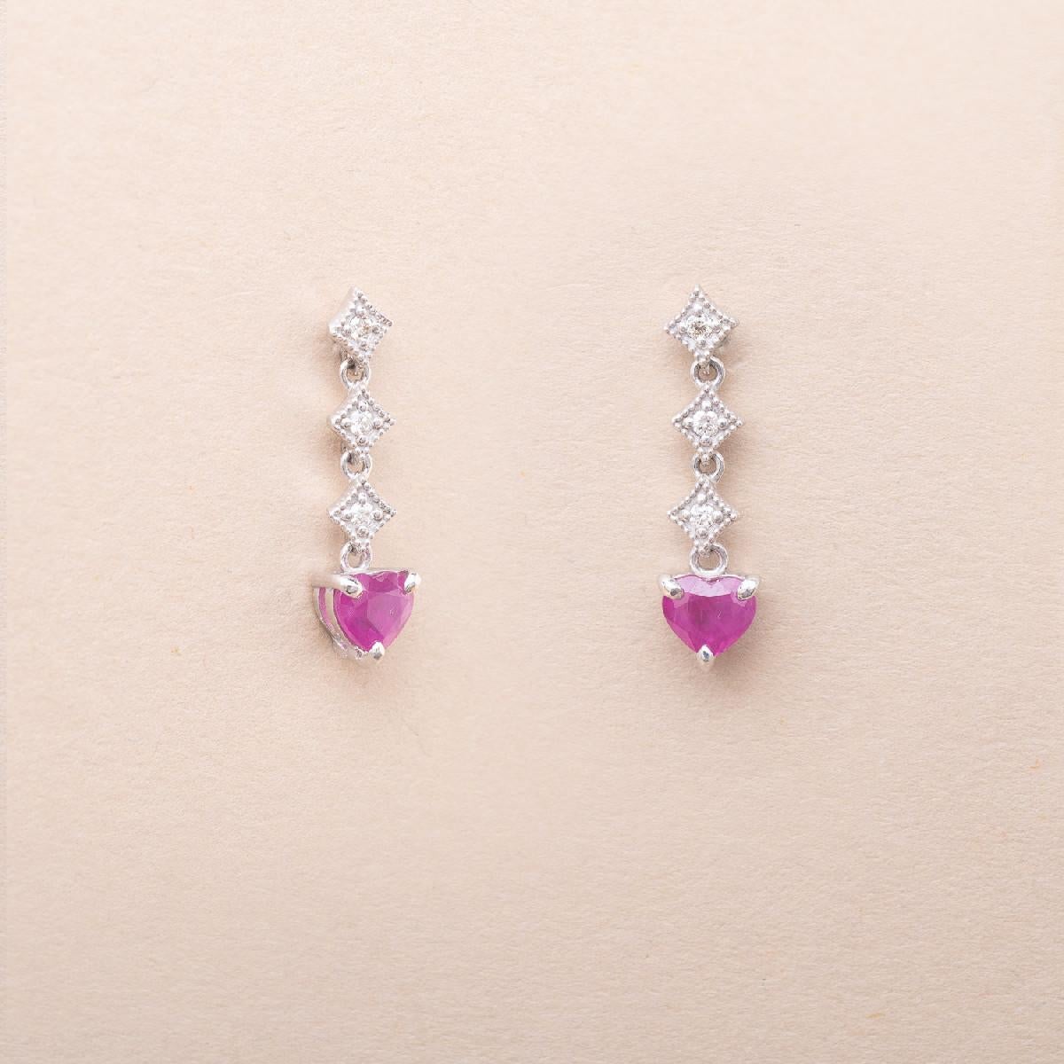 18K white gold dangle earrings set with six modern cut diamonds and two heart-shaped rubies. 

Rubies' estimated weight : 0.45 carat
Diamonds' estimated weight : 0.07 carat

Length : 2 cm

Total gross weight : 1.90 g