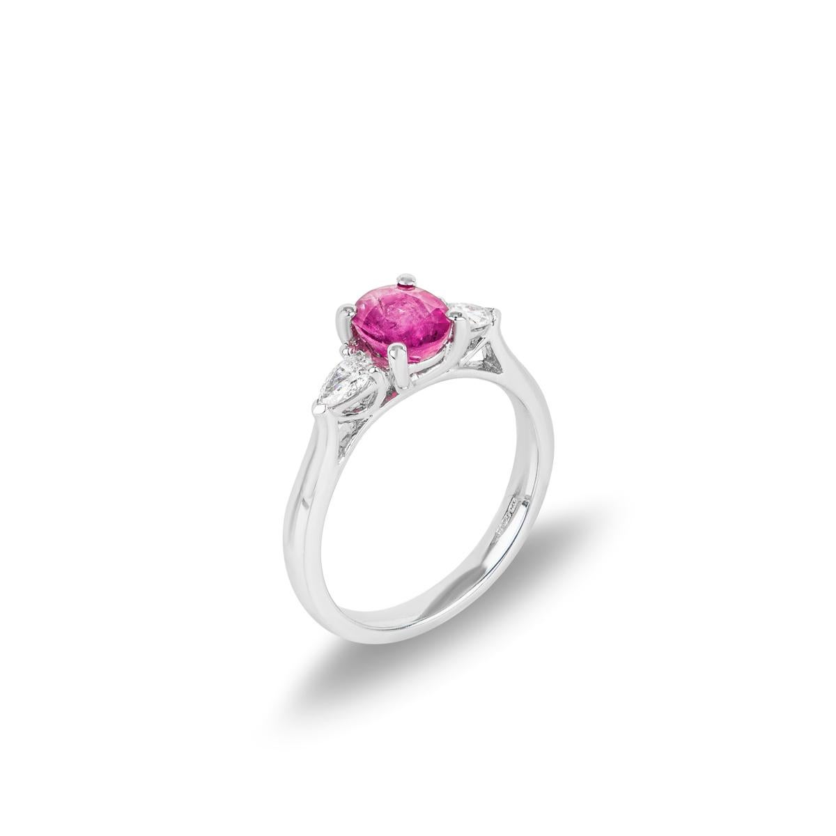 A classic 18k white gold ruby and diamond three stone ring. The ring features an oval cut ruby weighing 0.99ct set in a four claw mount. Further complementing the ruby are two pear cut diamonds set to either side with an approximate total weight of