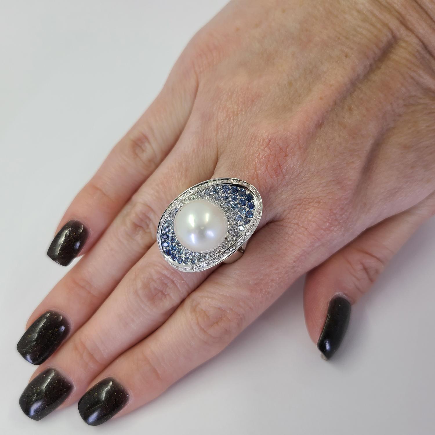 18 Karat White Gold Ring Featuring a 12.7mm South Sea Cultured Pearl, 2 Carat Total Weight Ombre Sapphires, & 0.15 Carat Total Weight Diamonds. Protective Concave Design With Openwork Sides. Finger Size 8.25; Purchase Includes One Sizing Service.