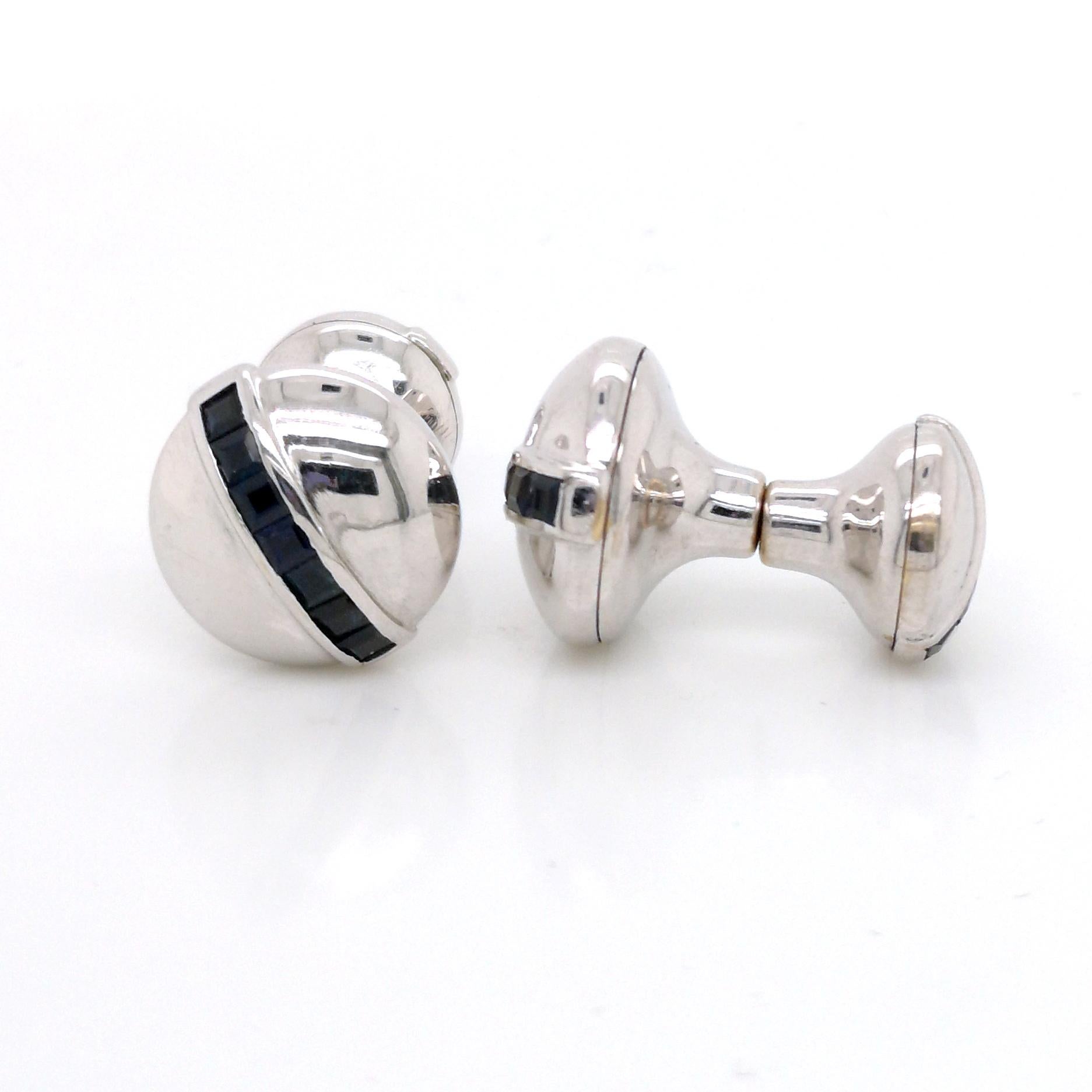 A pair of white gold cufflinks, comprised of a circular dome to each end, set with a single row of calibré cut sapphires, mounted in 18ct white gold, with sprung fittings.
