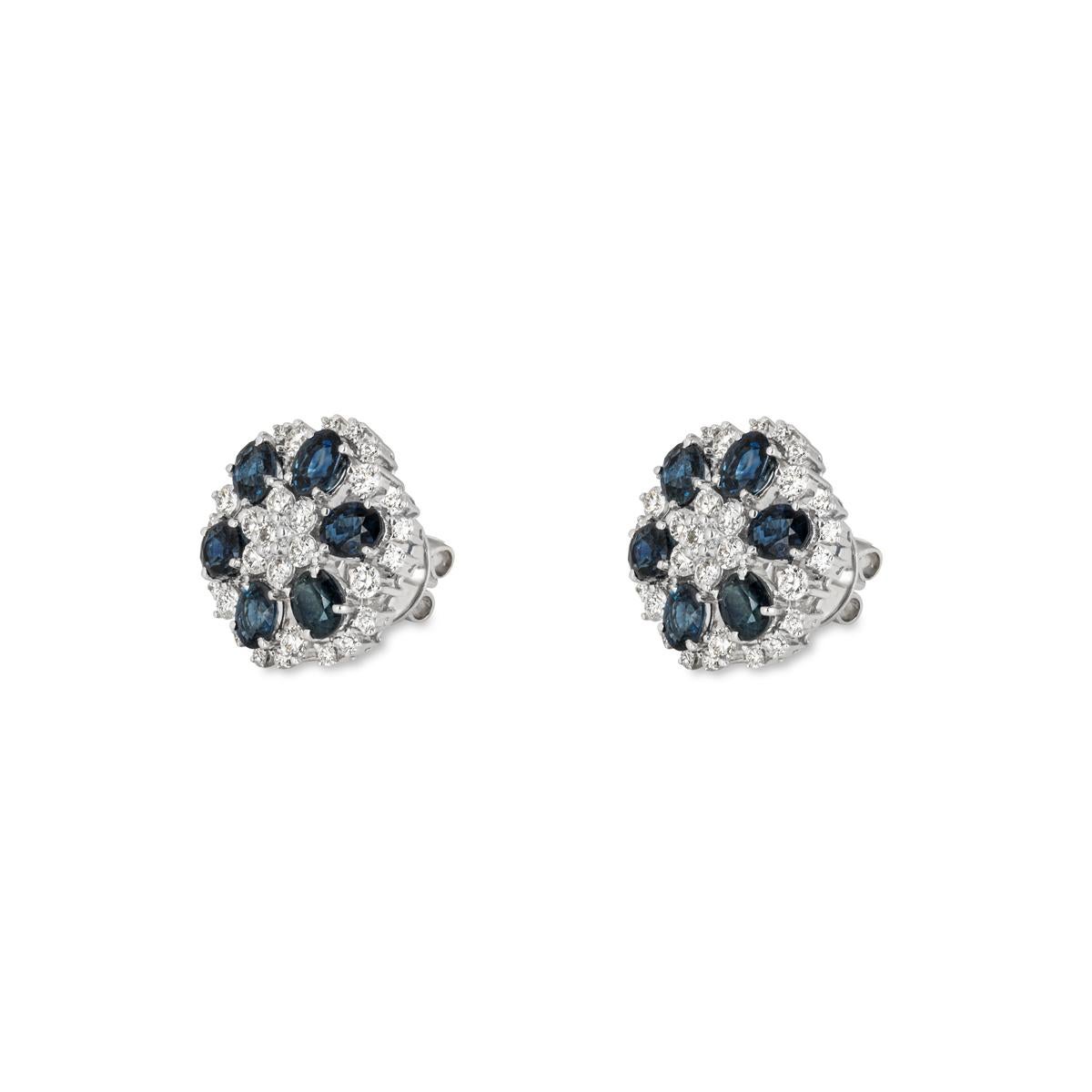 A striking pair of sapphire and diamond stud earrings. The floral earrings comprise of 62 diamonds and 12 sapphires alternating from the centre out. The round brilliant cut diamonds have a total weight of 1.79ct, G-H colour and VS clarity. The oval