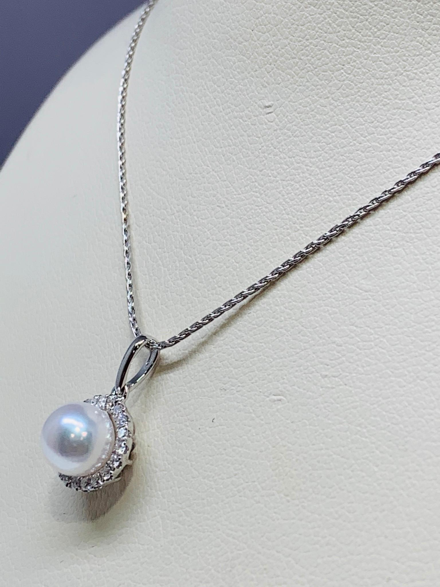 This timeless necklace features a 7.0 millimeter freshwater pearl set in a micro-pave diamond halo. This necklace holds 0.15 carats of round white diamonds surrounding the pearl. This necklace also includes a 0.8 millimeter white gold wheat style