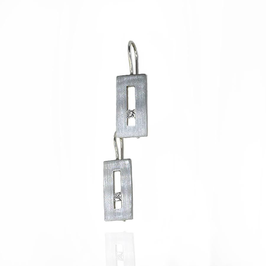 These Diamond in White Gold Suspended Rectangle hook earrings from our Suspension Collection echo the idea of princess cut diamonds set off center. Shown in white gold with approximately .20 pts diamond total weight in a matte finish. Available in