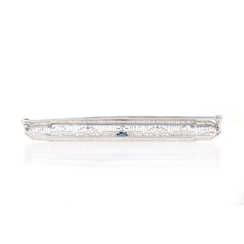 Era: Art Deco
Date: 1920s - 1930s

Metal Content: 10k White Gold

Stone Information
Synthetic Sapphire
Color: Blue

Style: Bar Brooch
Fastening Type: Hinged Pin and Locking C-Clasp
Features: Floral milgrain filigree design

Measurements
Tall: 11/32
