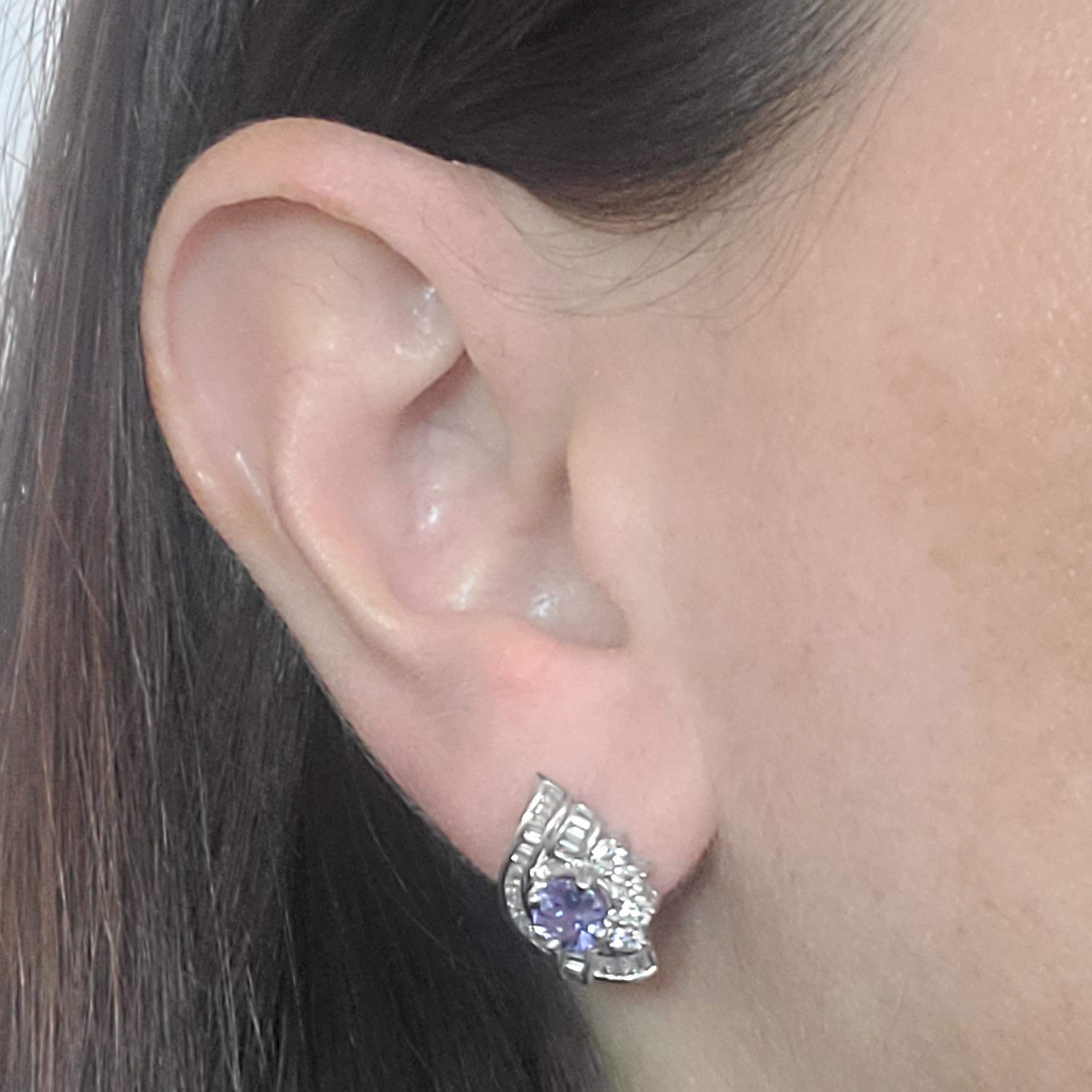 18 Karat White Gold Stud Earrings Featuring 2 Round Tanzanites Totaling Approximately 1 Carat, Accented By 58 Round and Baguette Cut Diamonds of VS Clarity and G/H Color Totaling Approximately 1 Carat. Pierced Post with Friction Back. Finished