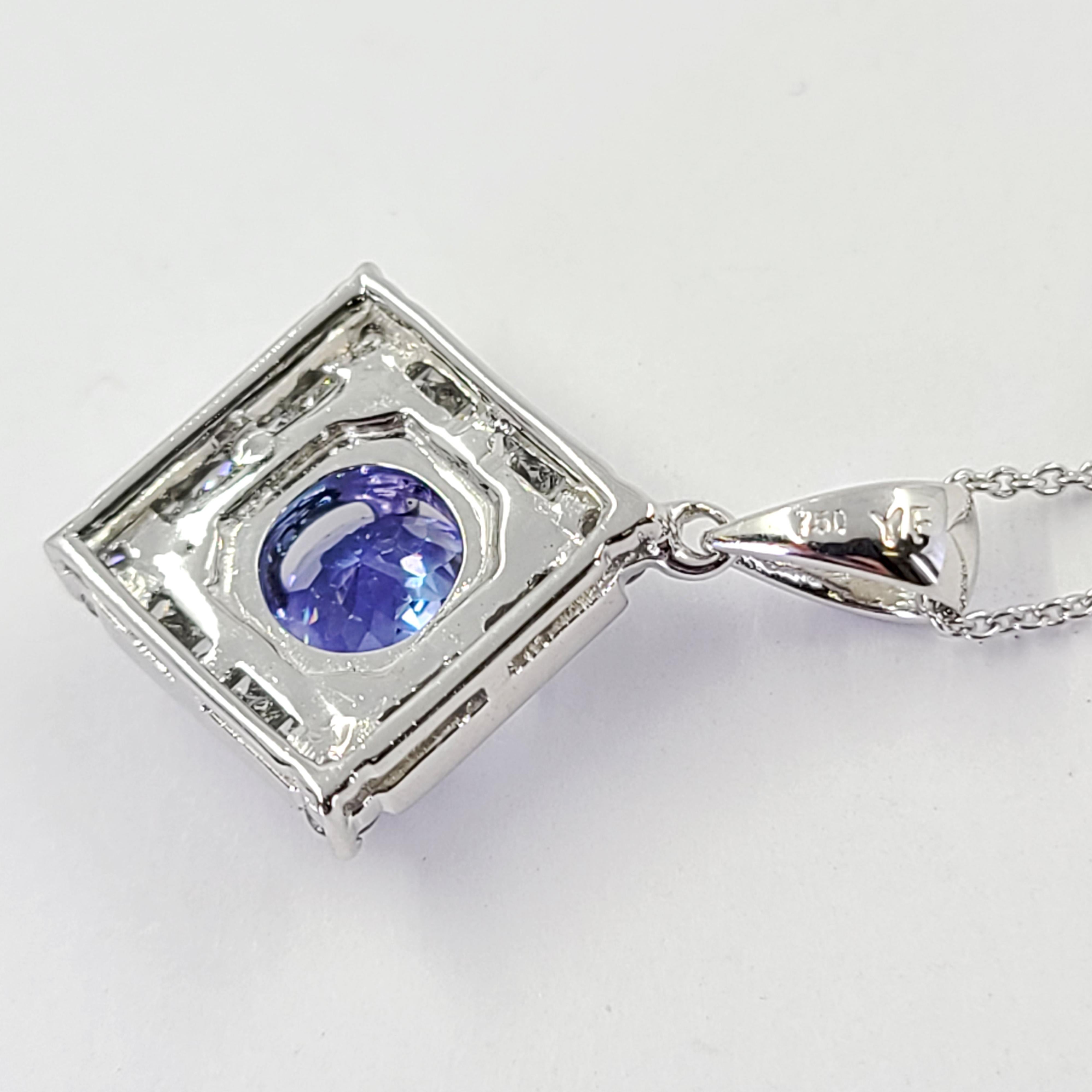 18 Karat White Gold Pendant Featuring A 0.85 Carat Round Tanzanite Surrounded By 20 Princess Cut Diamonds of VS Clarity and G Color Totaling 0.50 Carats. 1 Inch Length Including Bale. 16 inch rolo chain with lobster clasp.