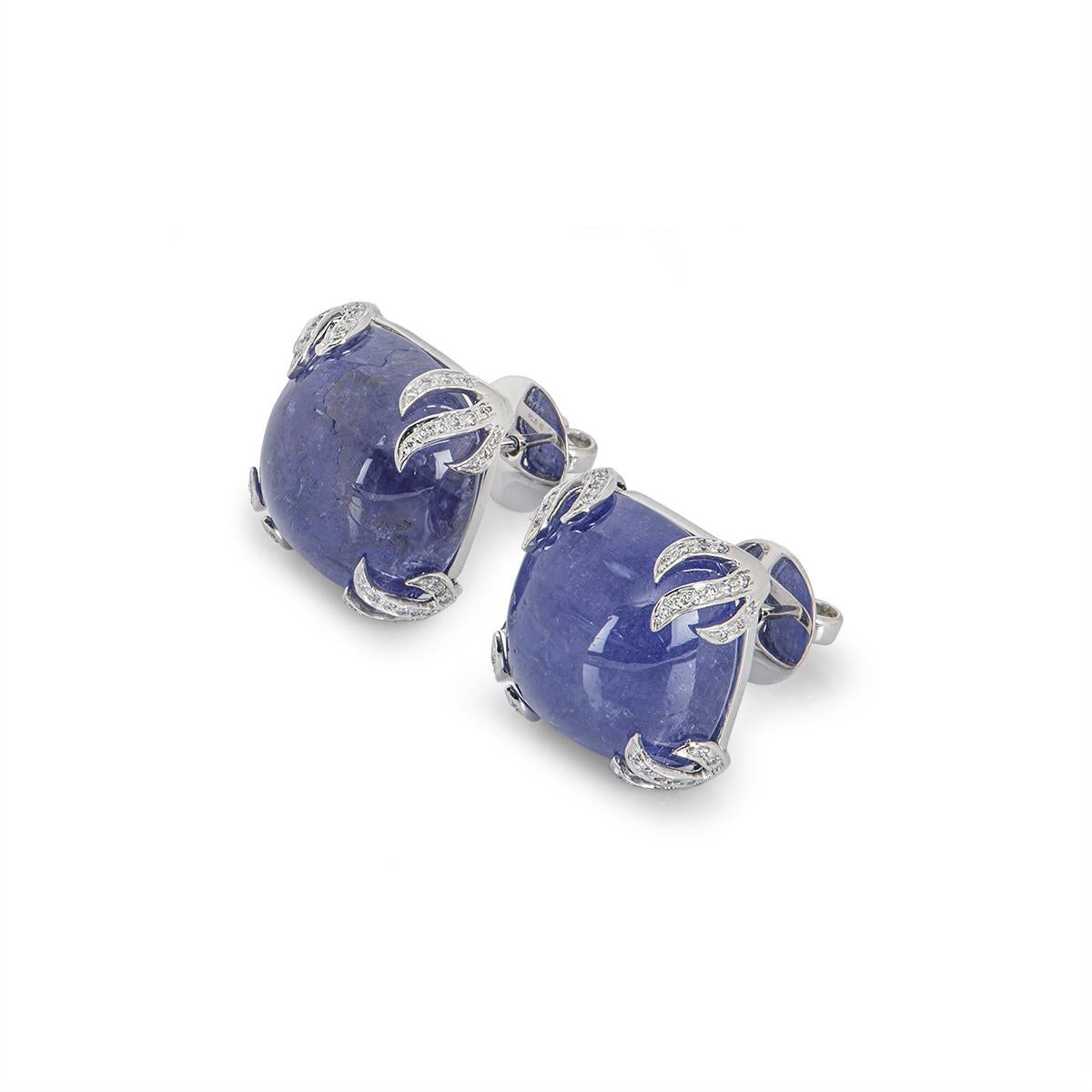An exquisite pair of tanzanite and diamond stud earrings. The earrings feature two cushion cut cabochons with an approximate weight of 48.65ct with a strong bluish violet hue set in a fancy four claw setting. The tanzanites are further complemented