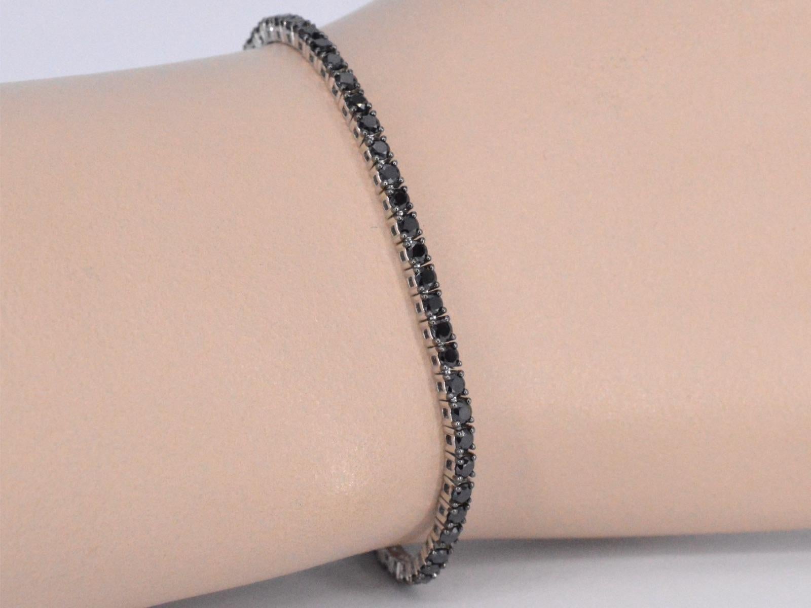 This beautiful tennis bracelet features a sleek and elegant design, crafted from high-quality white gold and set with dazzling black diamonds. The diamonds are expertly placed along the length of the bracelet, creating a continuous and sparkling