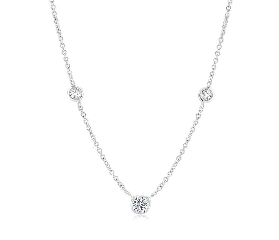 Fourteen karat white gold necklace pendant with three graduating bezel-set diamond 
Measuring 16 inch long
Center Diamond weight 0.15 carat
Two side Diamonds weight 0.05 carat each 
Thin cable chain necklace with spring lock: a lock that fastens