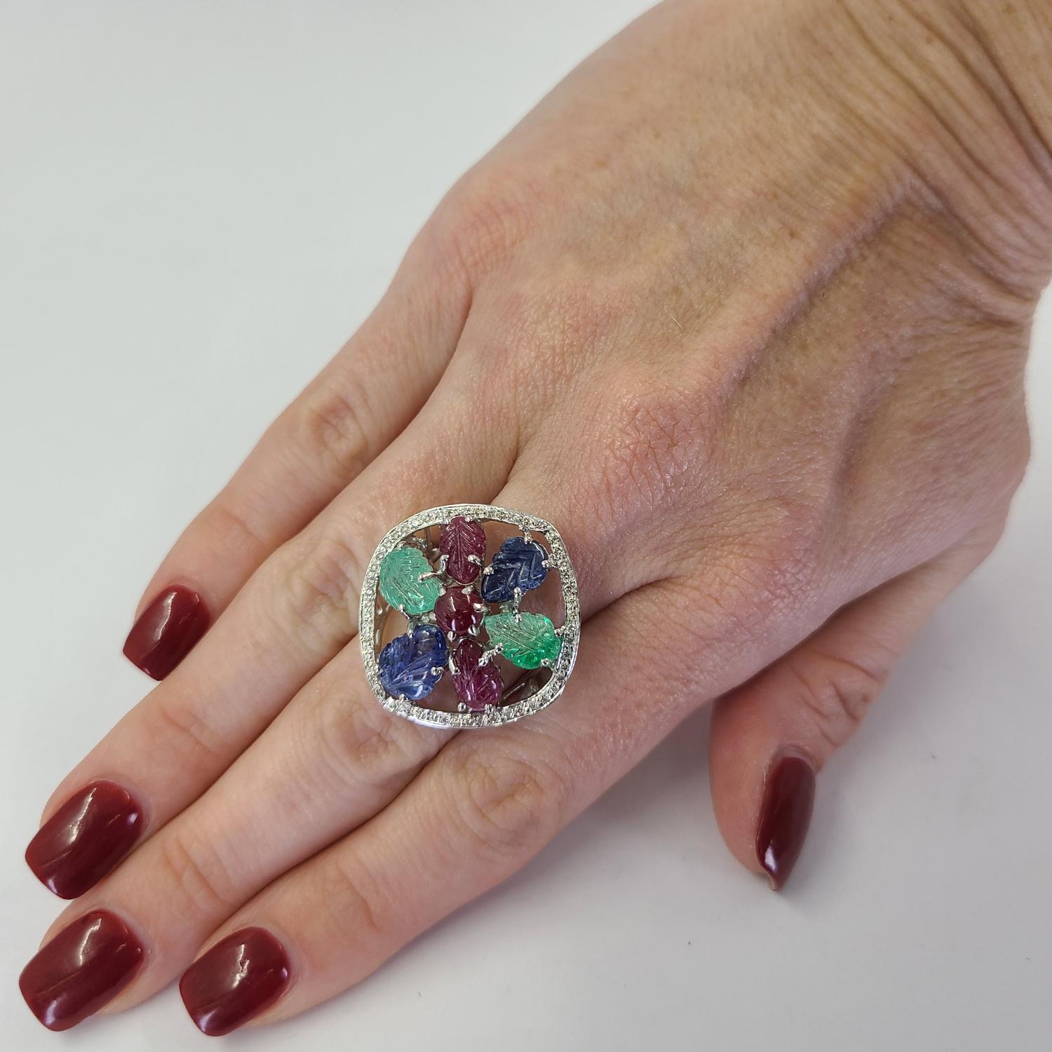 Inspired by Indian royalty, this 18 Karat White Gold Tutti Frutti Style Ring Features Carved Emerald, Ruby, & Sapphires Accented By 50 Round Brilliant Diamonds Totaling 0.25 Carats. Finger Size 7; Purchase Includes One Sizing Service. Finished