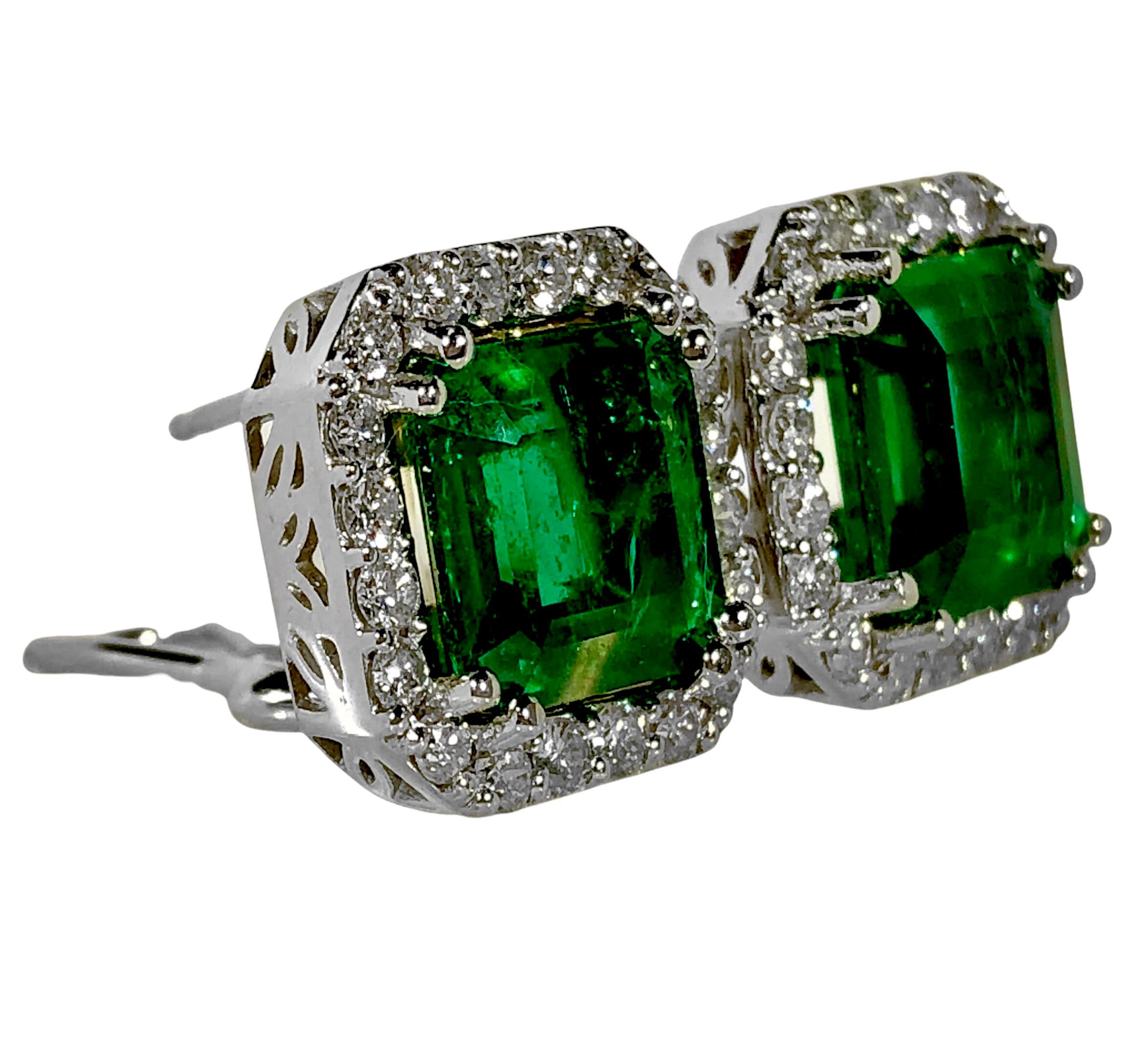 A pair of 14K white gold earrings set with two Zambian emerald cut emeralds weighing a total of exactly 7.96 carats. The edges of the earrings are set with a total of 40 round brilliant cut diamonds, weighing a total of approximately 1.50ct of