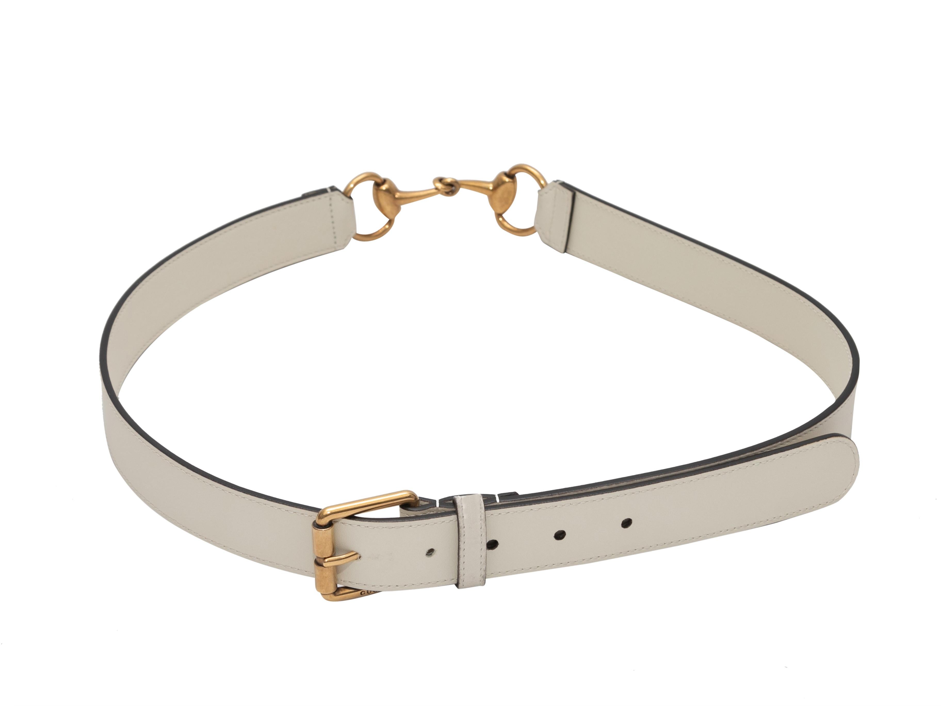White leather belt by Gucci. Gold-tone hardware. Horsebit accent at back. Front buckle closure. 1