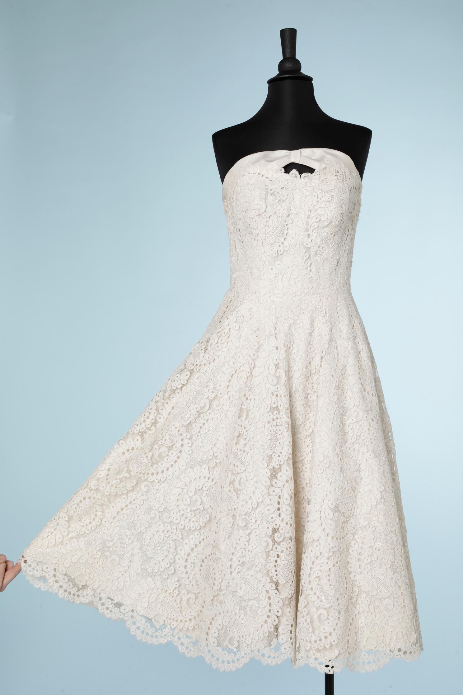 Weißes Guipure-Bustier-Hochzeitskleid. Unterkleid mit entbeintem Bustier und Reißverschluss am Rücken sowie Haken- und Ösenverschluss am Tüllunterrock. Zweiter Reißverschluss oben auf dem 1. in der Mitte des Rückens, um das Kleid zu schließen.
