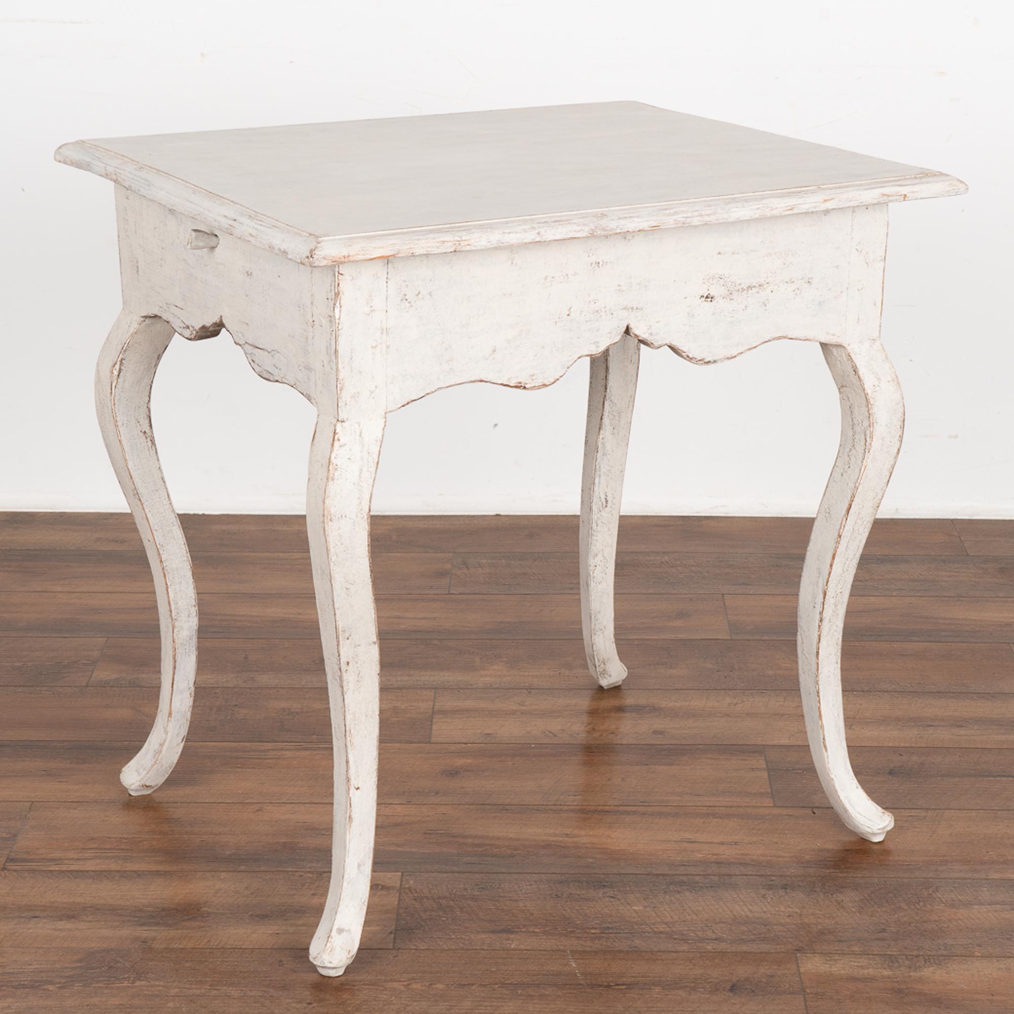 Swedish Gustavian side table with cabriolet legs and large scalloped skirt. 
Restored, later professionally painted in layered shades of white and gently distressed to compliment the age and grace of this lovely accent table. 
Any old nicks,