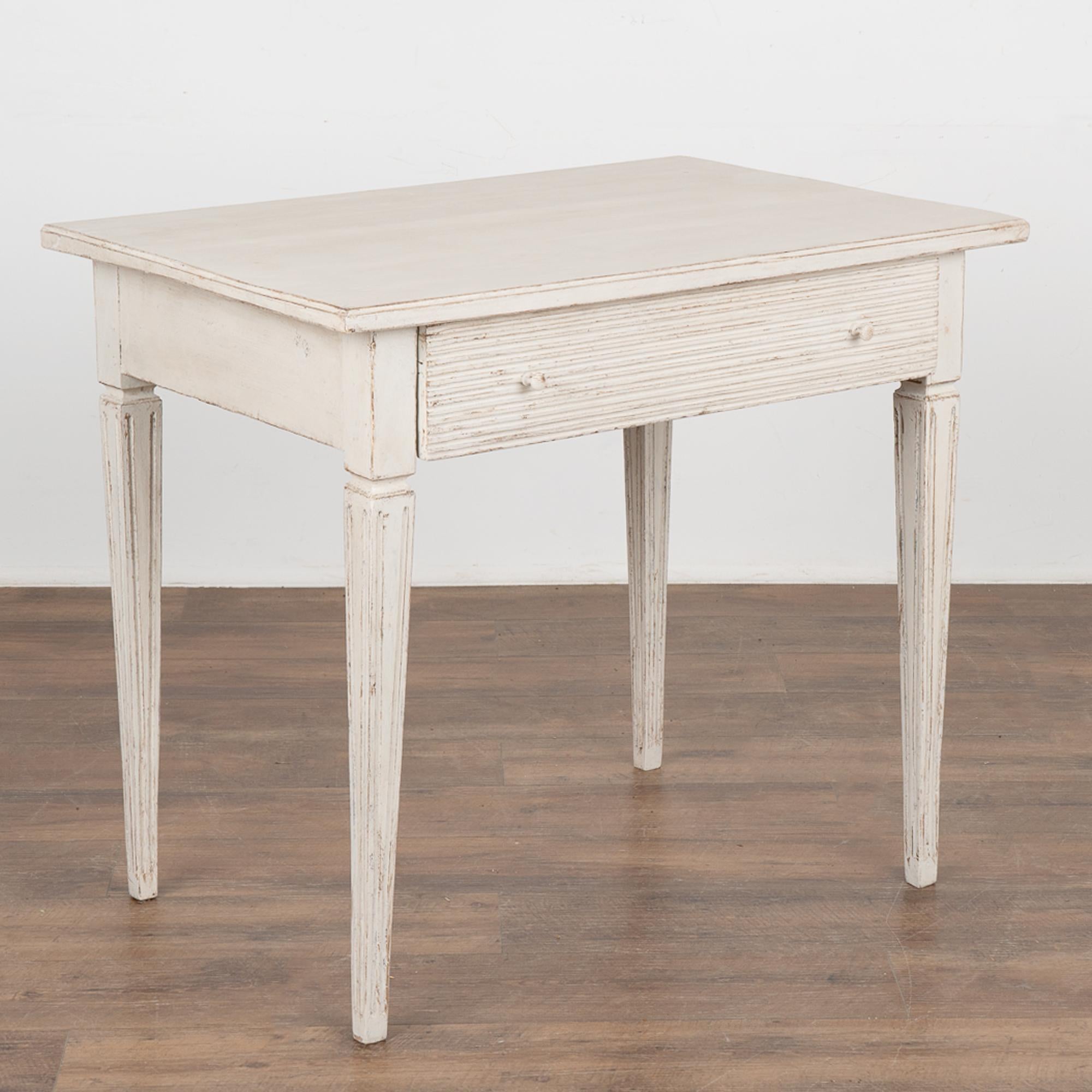 Antique Swedish Gustavian White Painted Side Table With Drawer.
Tapered fluted legs and horizontal fluted carving along single drawer. May also serve as nightstand or small desk.
Floor to skirt height: 24