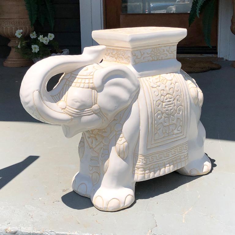 Cream happy elephant good luck ceramic garden stool or side table. Featuring Chinese symbols glazed in a cream white glaze throughout. 

In this particular piece, the elephant has his trunk up. A symbol of happiness and good luck in most Asian