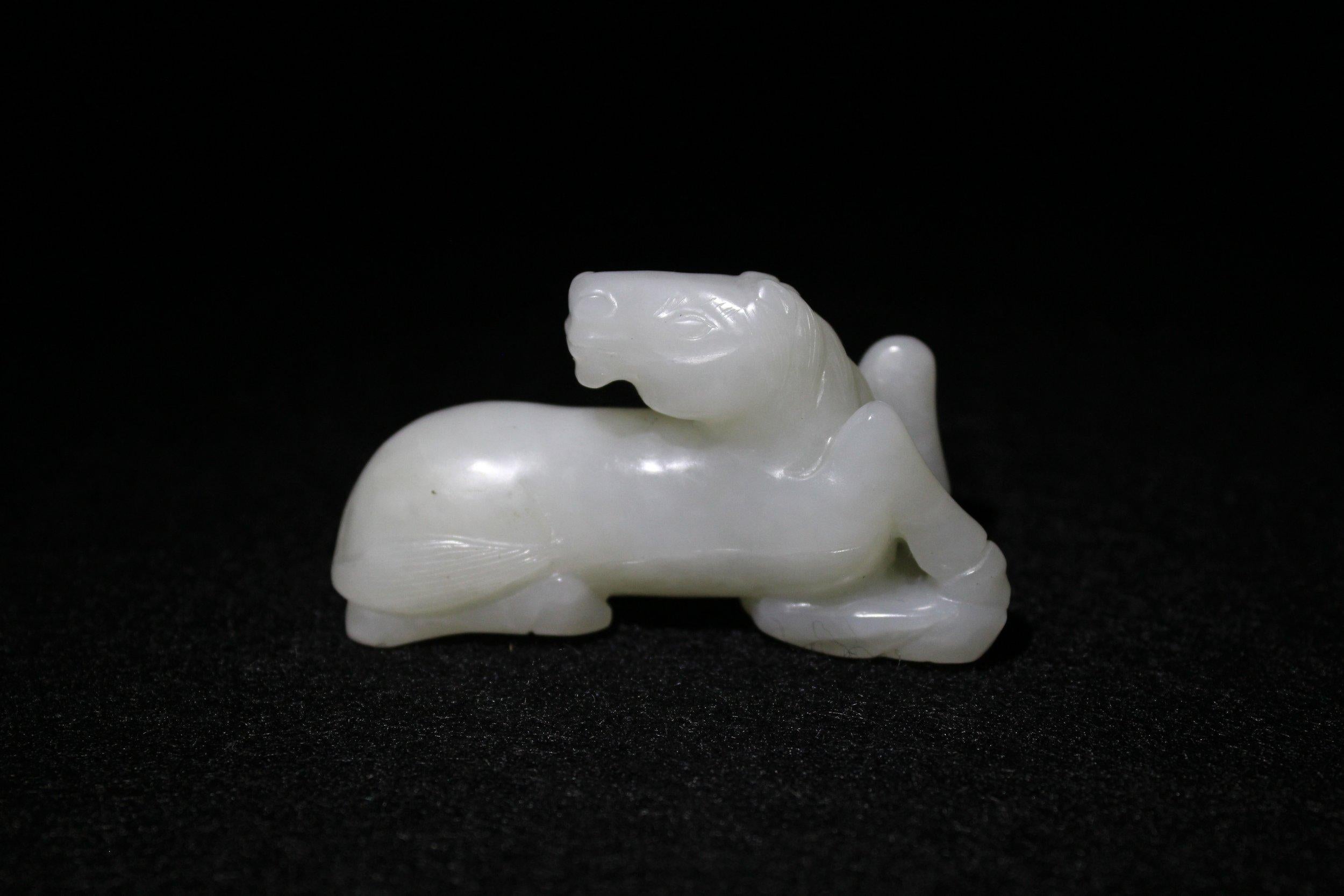 Un cheval au repos a été sculpté dans du jade Hetian lustré d'une couleur blanche uniforme. Le long corps musclé repose sur quatre pattes pliées et la tête est retournée. 

La crinière est ornée de longues mèches striées qui s'étendent sur la nuque,