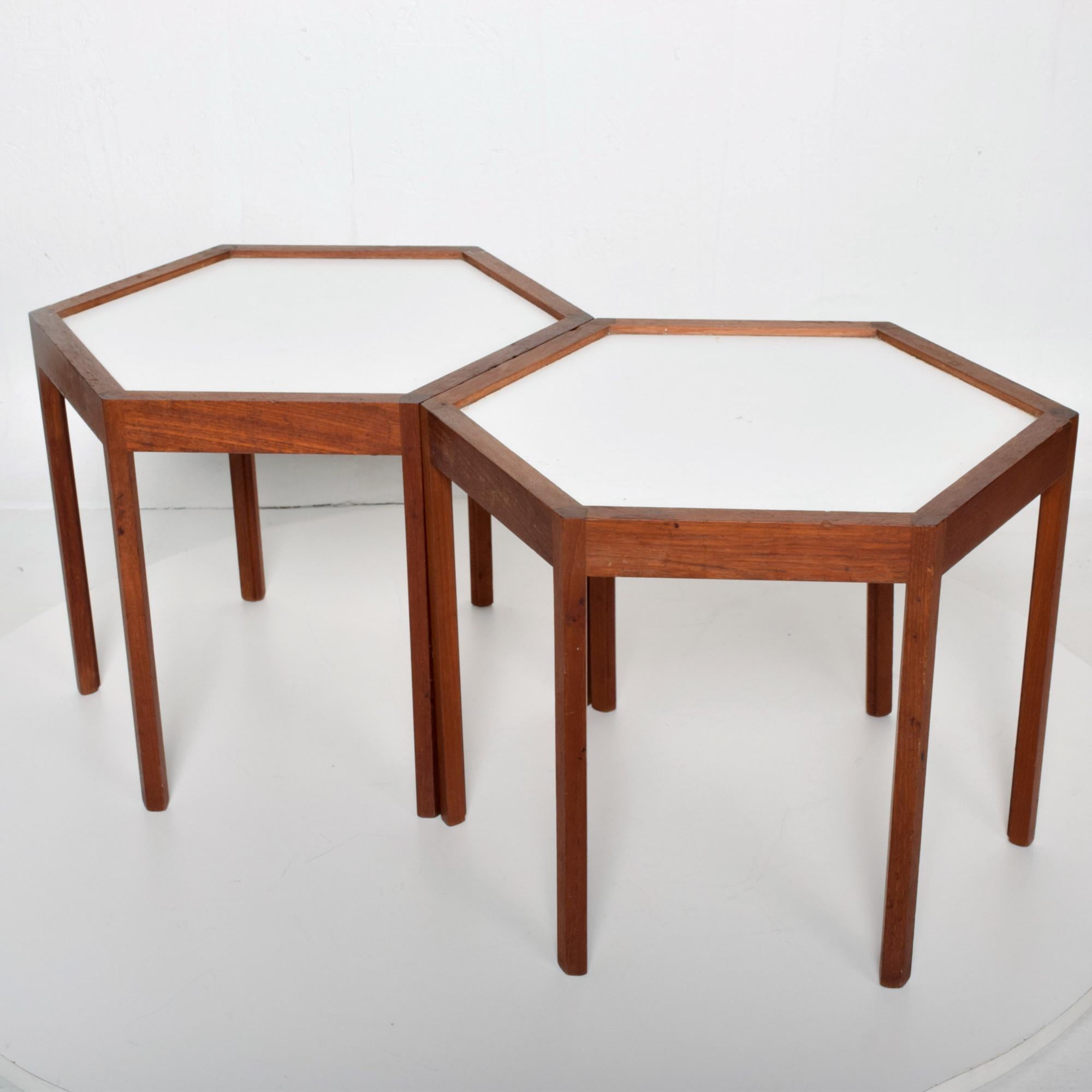 Hexagonal pair of side tables by Hans C Andersen. Made in Denmark circa 1960s. 
Hexagon shape with solid teak wood and white laminate Formica table top.
Dimensions: 14.5 height x 19 in diameter.
Overall good condition. Recently oiled. Expect