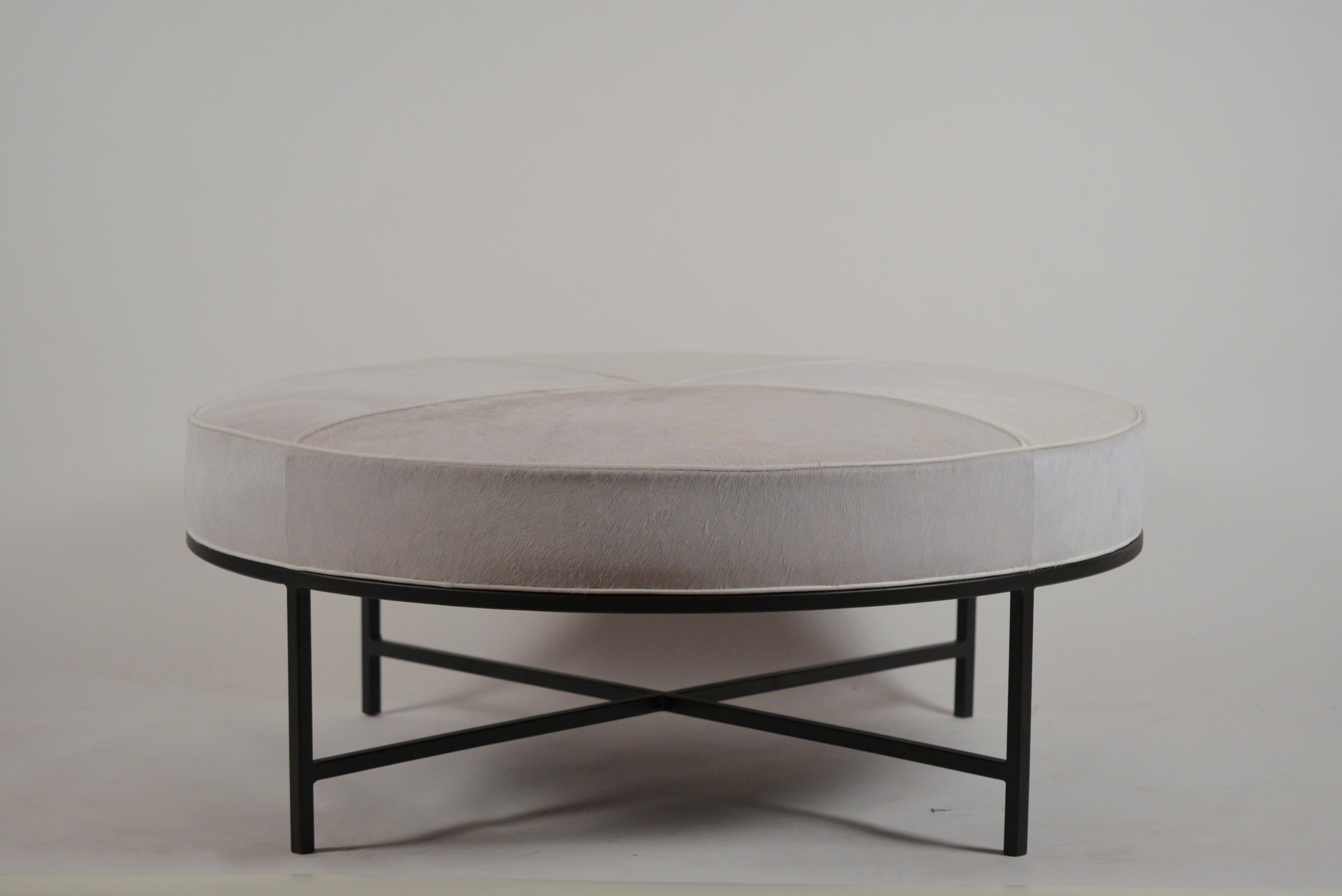 White hide and matte black 'Tambour' round ottoman by Design Frères. Upholstered firm for use as an ottoman / coffee table. Great for dens / media rooms, with books, tray... or feet!