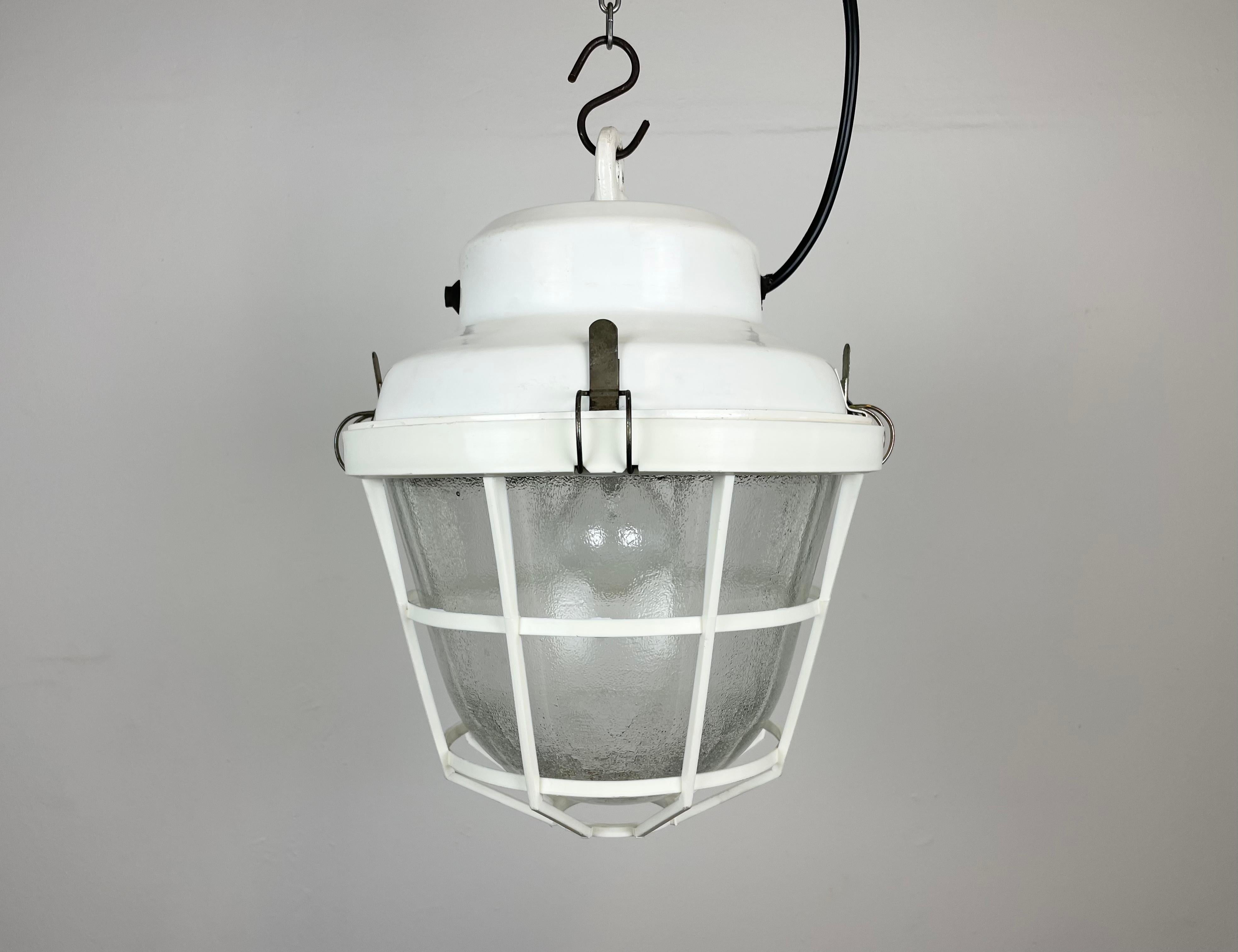 Lampe industrielle fabriquée par Elektrosvit dans l'ancienne Tchécoslovaquie au cours des années 1980. Il est doté d'un plateau en fer blanc, d'un verre dépoli et d'une grille de protection en plastique blanc.
La douille en porcelaine est compatible
