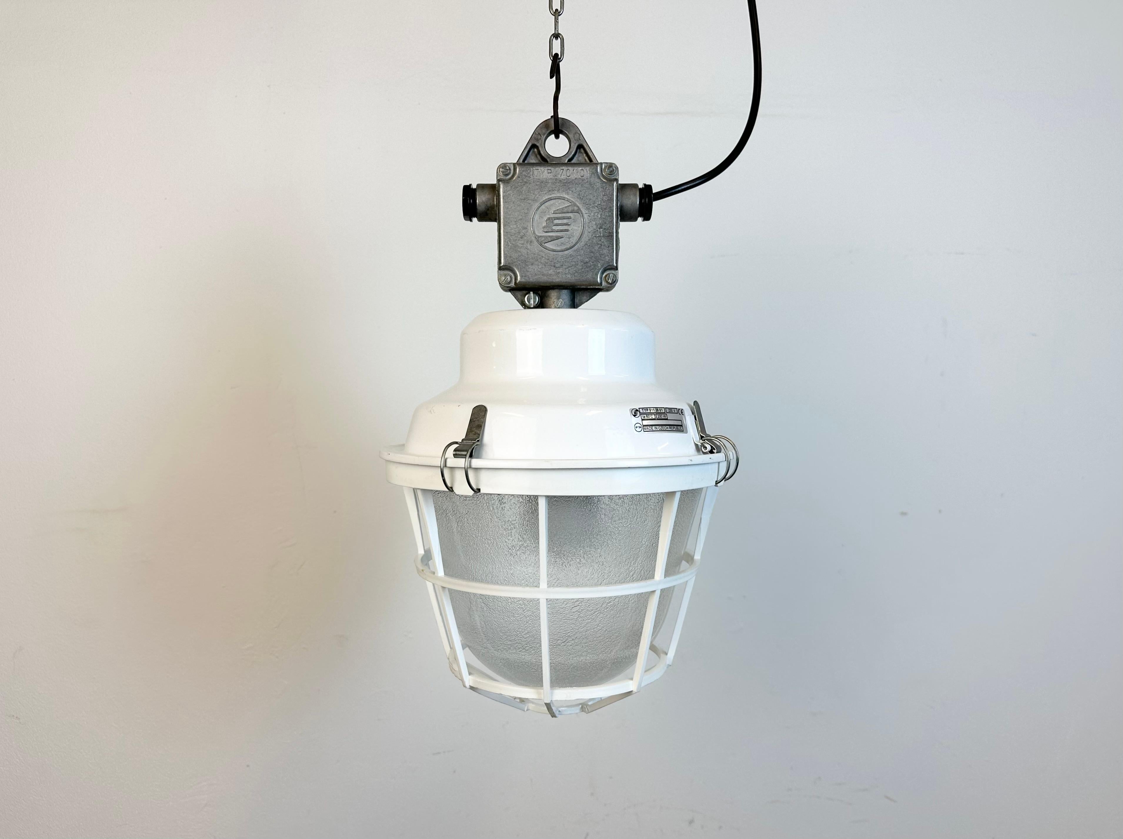 Industrial light made by Elektrosvit in Czech republic during the 1990s. It features a white iron top with cast aluminium box, a frosted glass and a white plastic protective grid.
The porcelain socket requires standard E27/ E26 lightbulbs. New wire.