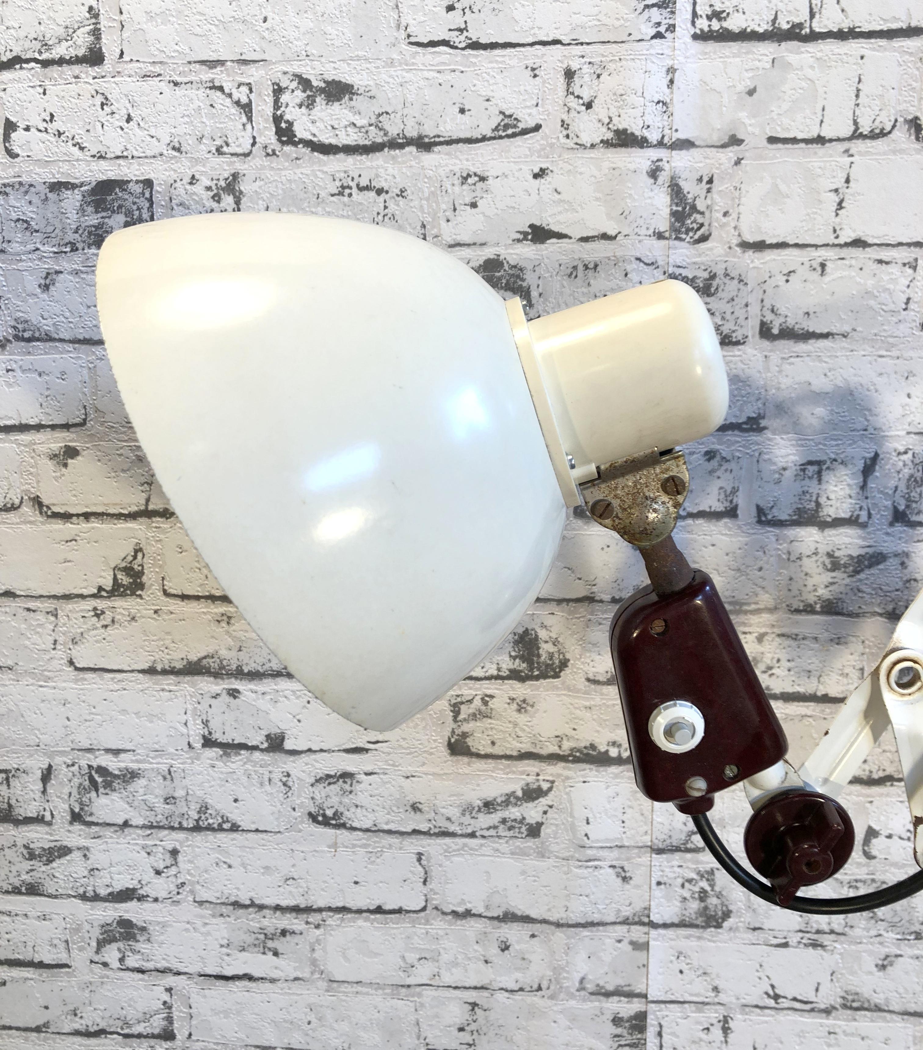 This vintage Industrial scissor lamp was produced by VEB Zweckleuchtenbau Dresden in former East Germany during the 1960s.Lamp has white Bakelite shade. White iron scissor arm is extendable and can be turned sideways. Original socket for E 27 bulbs.
