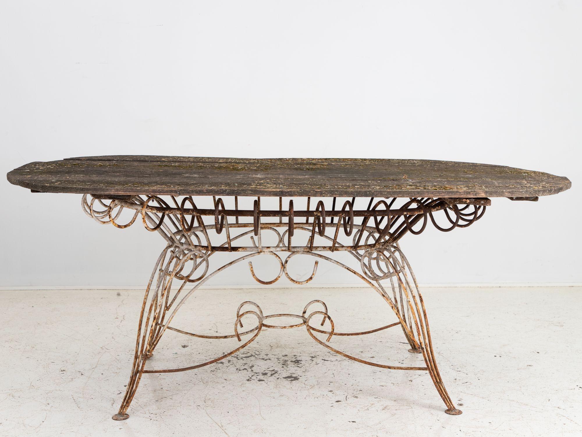 Dieser ovale französische Esstisch aus dem frühen 20. Jahrhundert hat eine spätere Holzplatte als Zeugnis der Handwerkskunst, verwittert und doch unverwüstlich. Darunter befindet sich ein kunstvoll geschwungener Eisensockel, der an die Feinheiten
