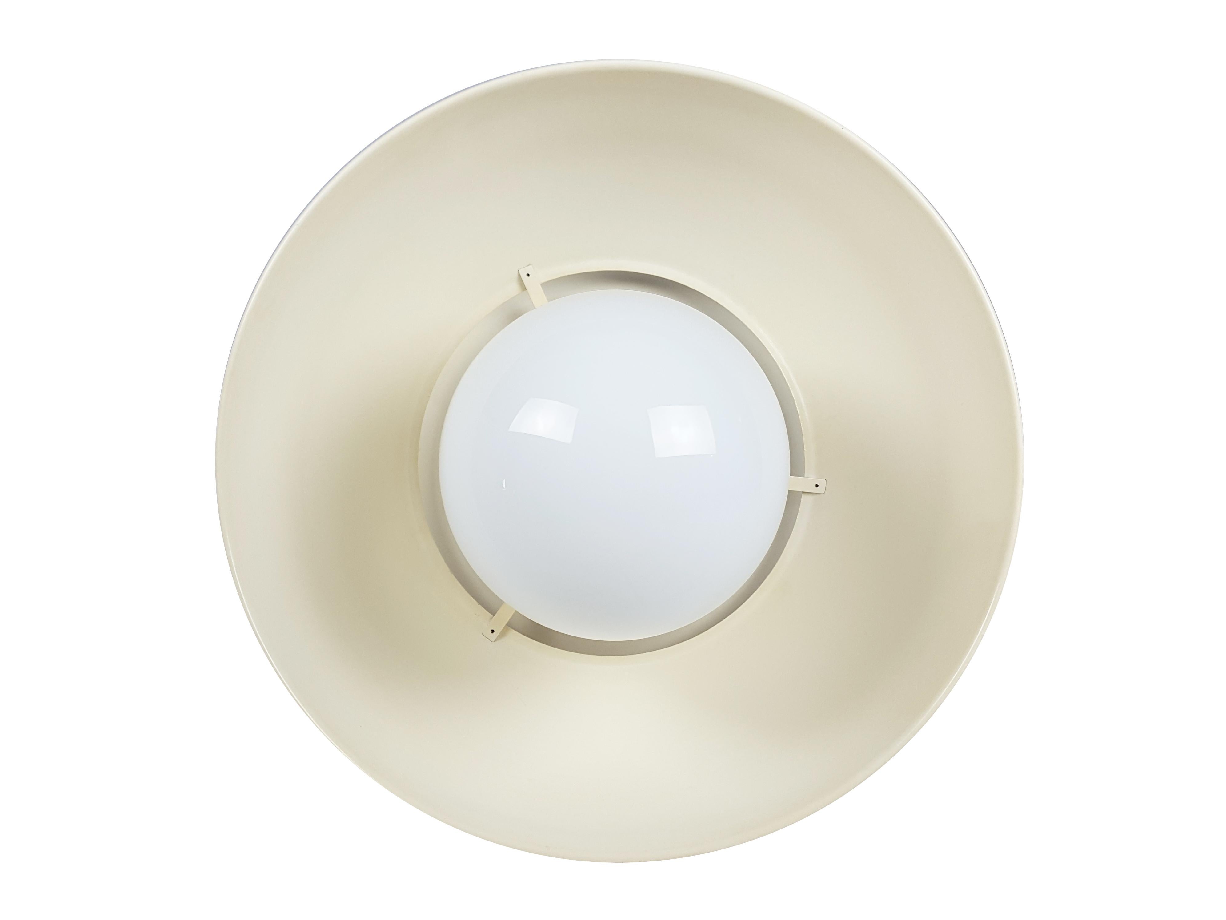 This vintage pendant was produced by Artemide with painted brass and metal shades and white opaline glass sphere. The white paint has turned yellow over time, taking on a pleasant and warm ivory color. The pendant rod shows visible paint lossed: on