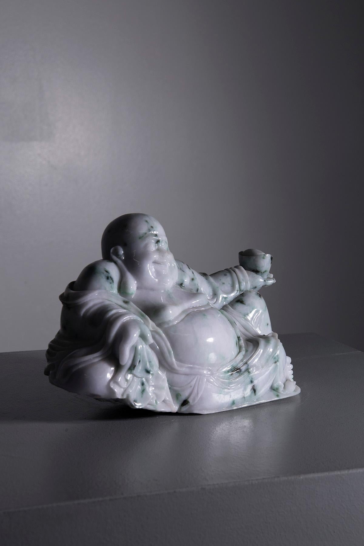 This jade sculpture exudes an aura of serenity and abundance that captivates and enchants. It represents the Buddha of happiness, with a radiant and smiling face that immediately conveys joy and inner peace. The generous forms, symbols of prosperity