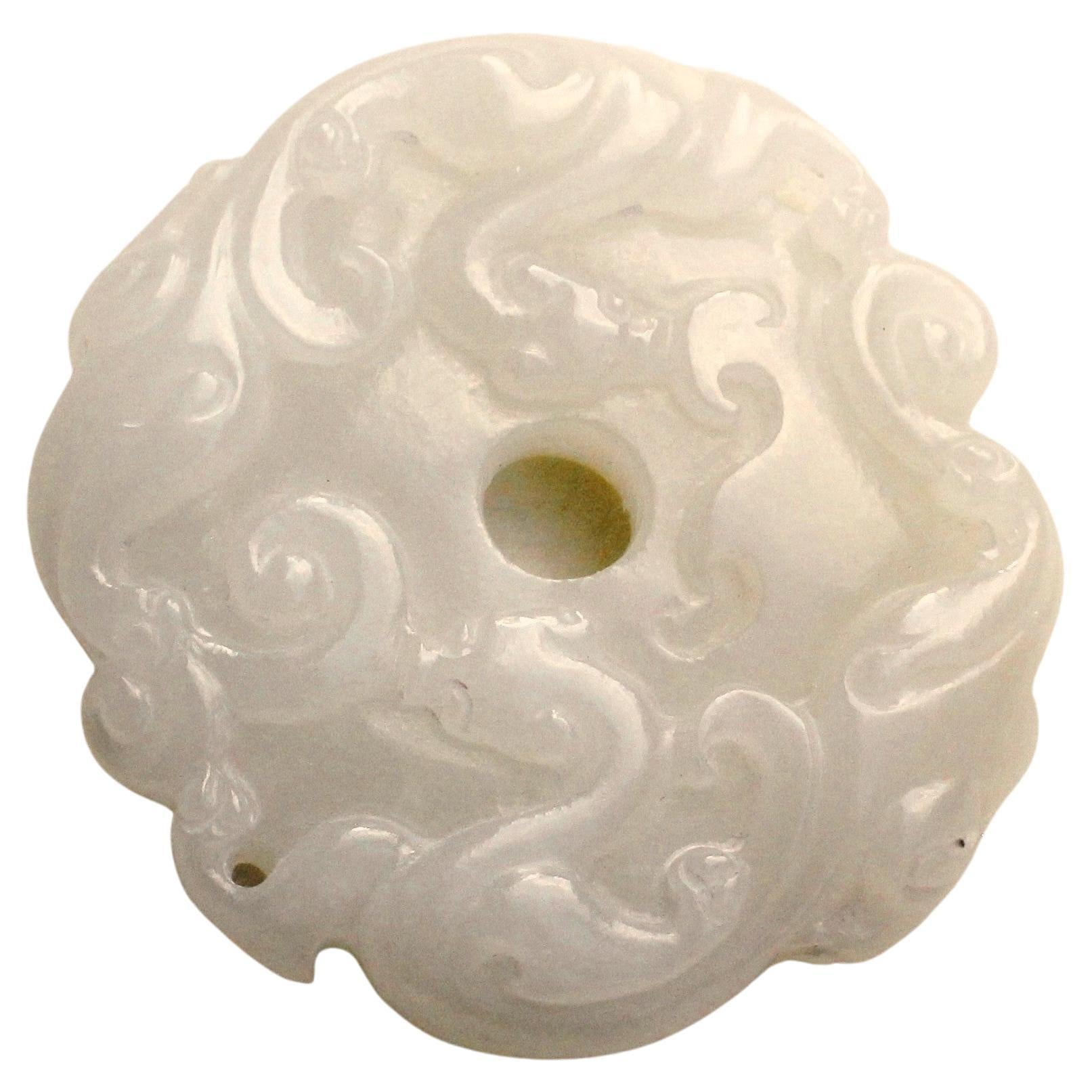Un ciondolo in giada bianca splendidamente intagliato, con un doppio motivo chilong intrecciato all'interno di un disco di nuvole, un disegno molto apprezzato nelle sculture di giada arcaiche della dinastia Ming e Qing. Il foro centrale rappresenta