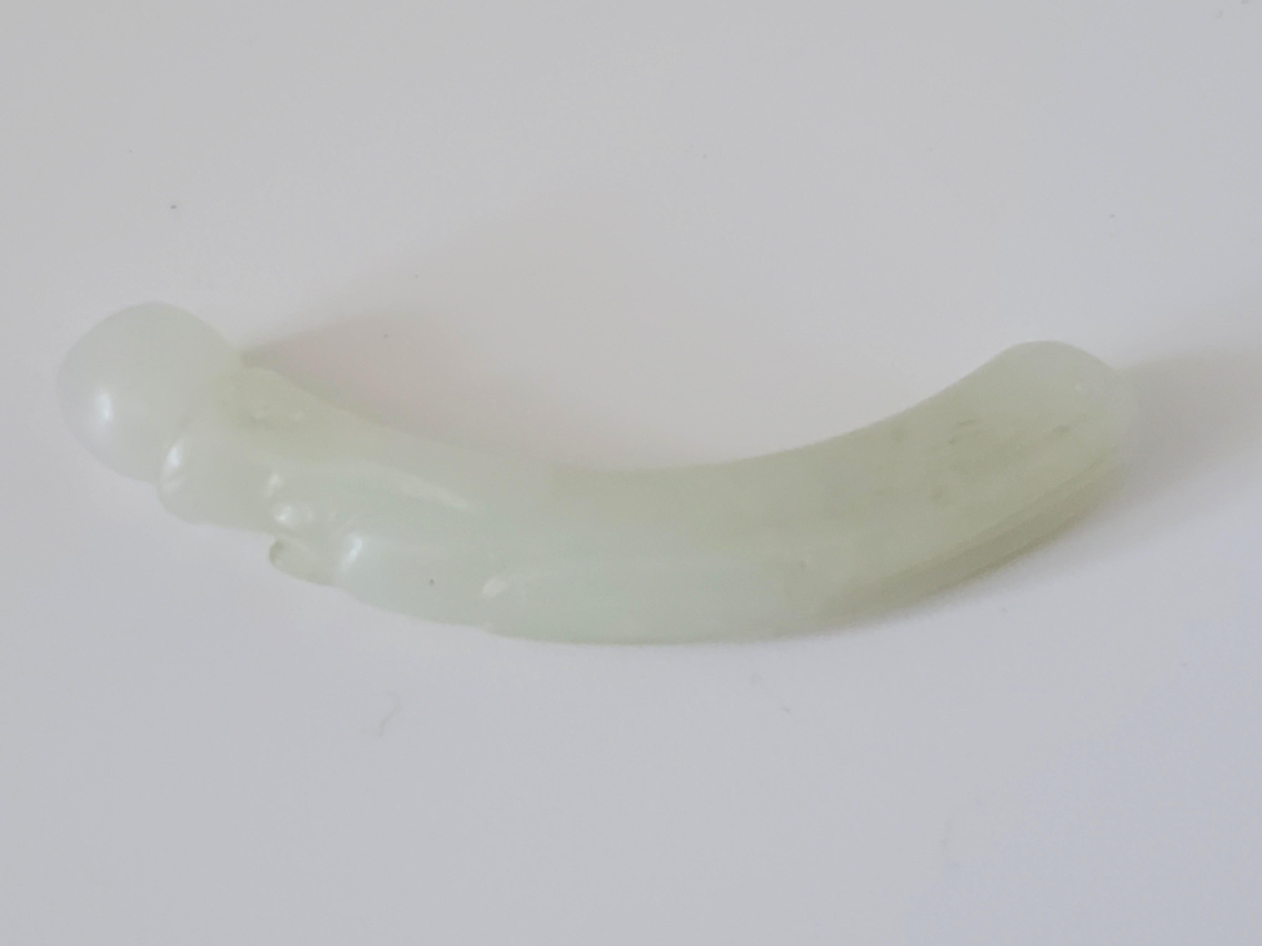 This antique Qing Dynasty nephrite jade pendant consists of a dragon with a pearl in its mouth. There is decorative etching on the body, and the head and mouth are well defined. The pendant has a semi-fine texture with a semi-gloss or slightly waxy