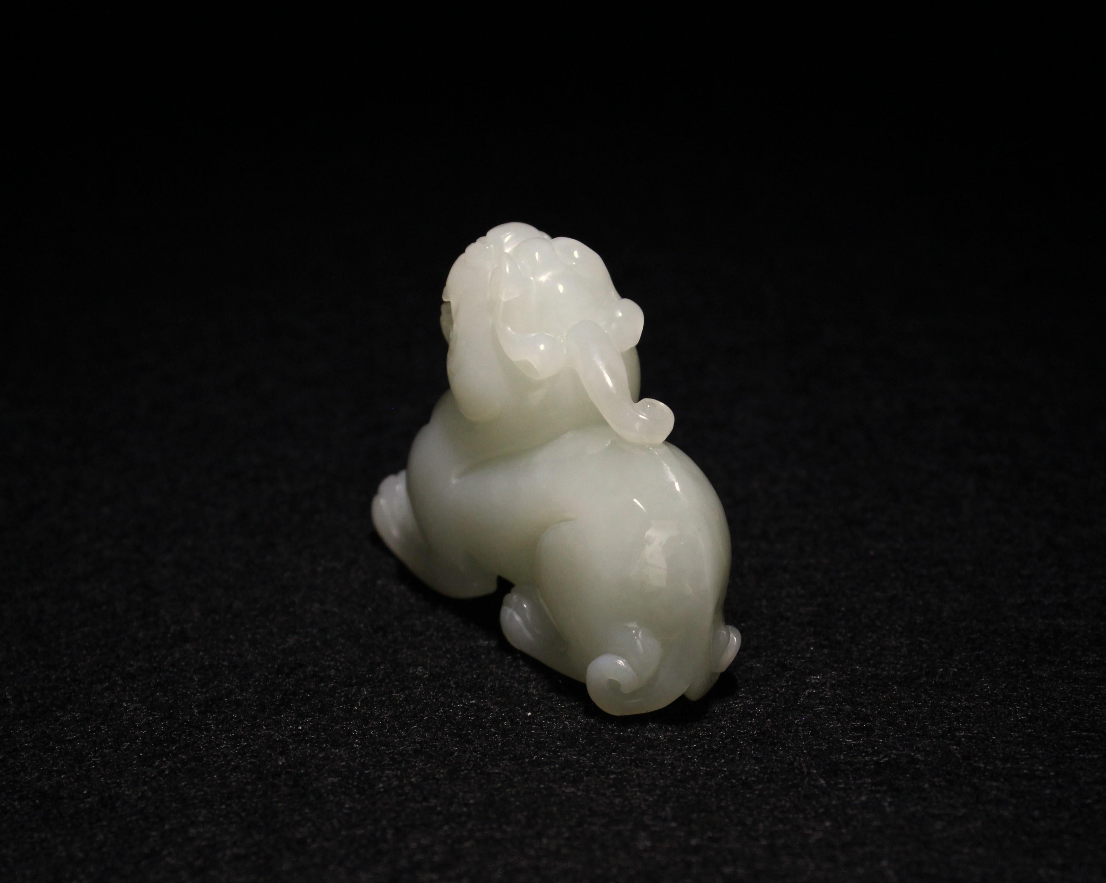 Une captivante sculpture en jade blanc d'un animal mythique unihorn, représenté dans une position accroupie, la tête levée, dégageant une aura de force et de mysticisme. Les yeux globuleux et les sourcils en forme de nuages de la créature ajoutent à