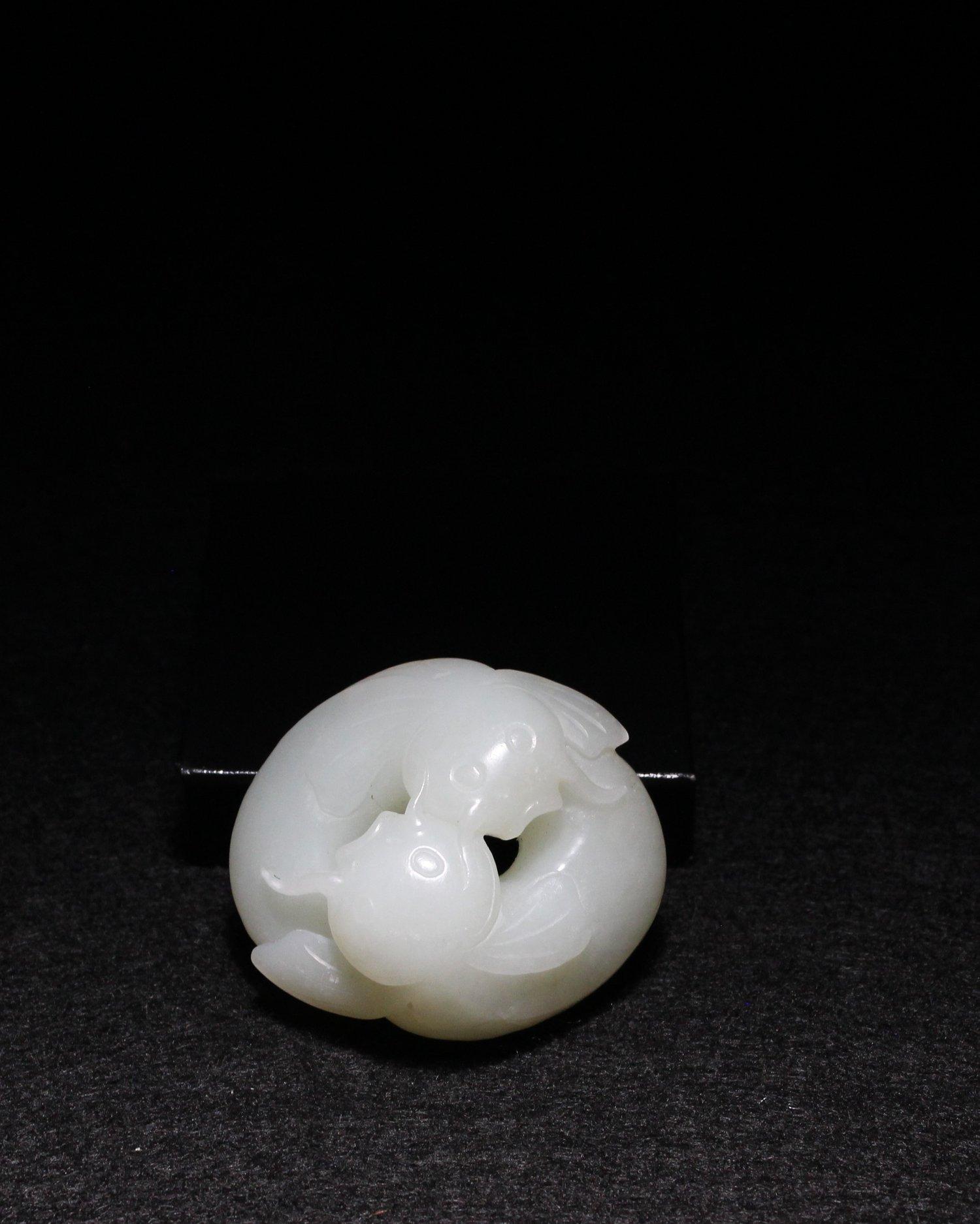 The two fish curling towards each other make a balanced, symmetrical piece, like yin and yang. They form a pendant that can be used as an ornament or toggle. The “mutton fat” white jade is highly polished. 

A similar piece can be seen in Later