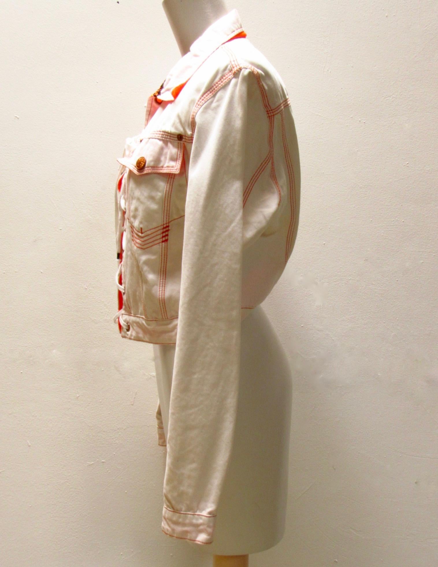 A white jacket from very vintage Jean Paul Gaultier features orange contrast stitching and a laced-up style front. Orange pockets, lining and removable velcro JPG patch on sleeve. 