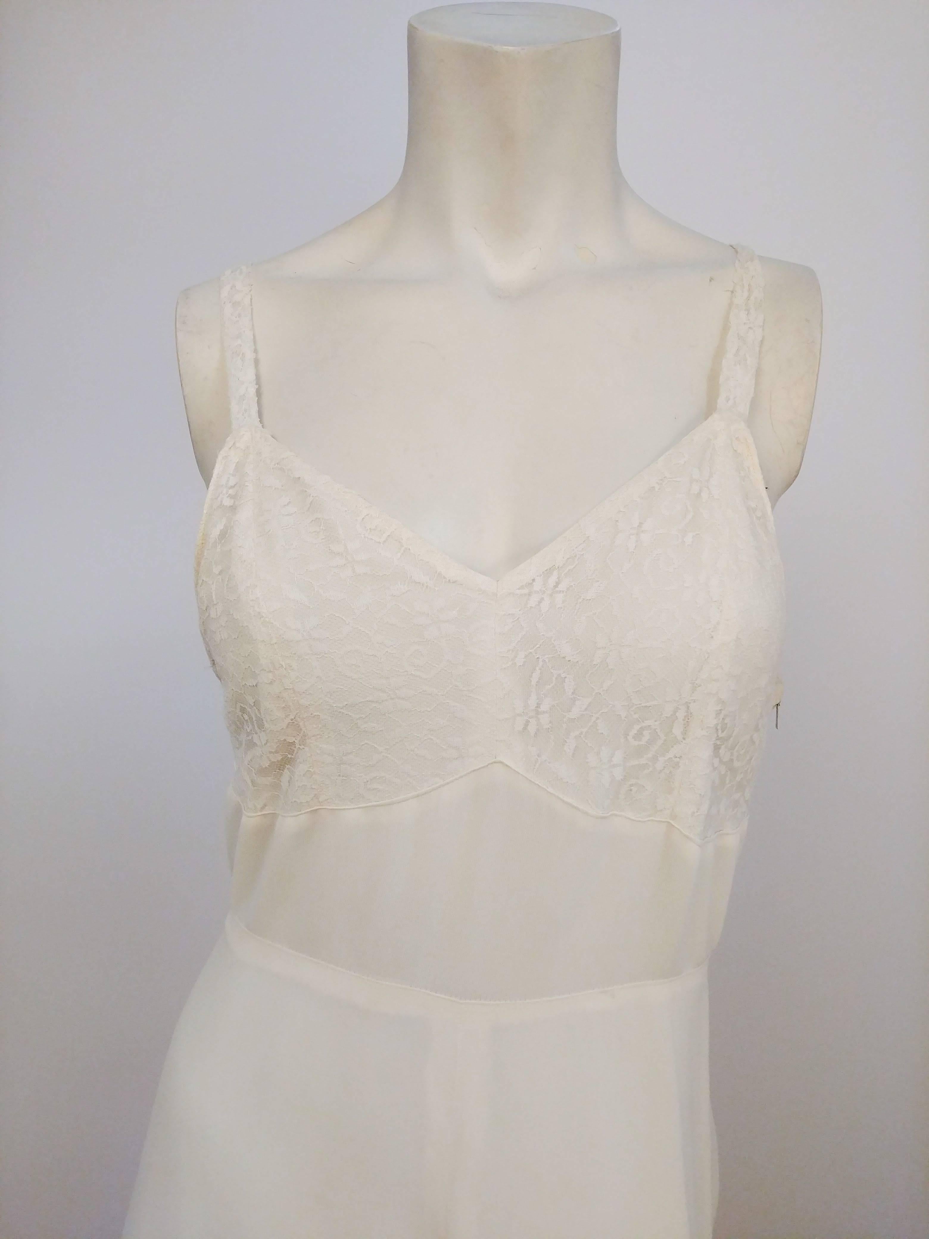 Robe à traîne en dentelle blanche, années 1930. Superposition de dentelle au niveau du buste, de la couture naturelle de la taille et de la jupe pleine longueur. 