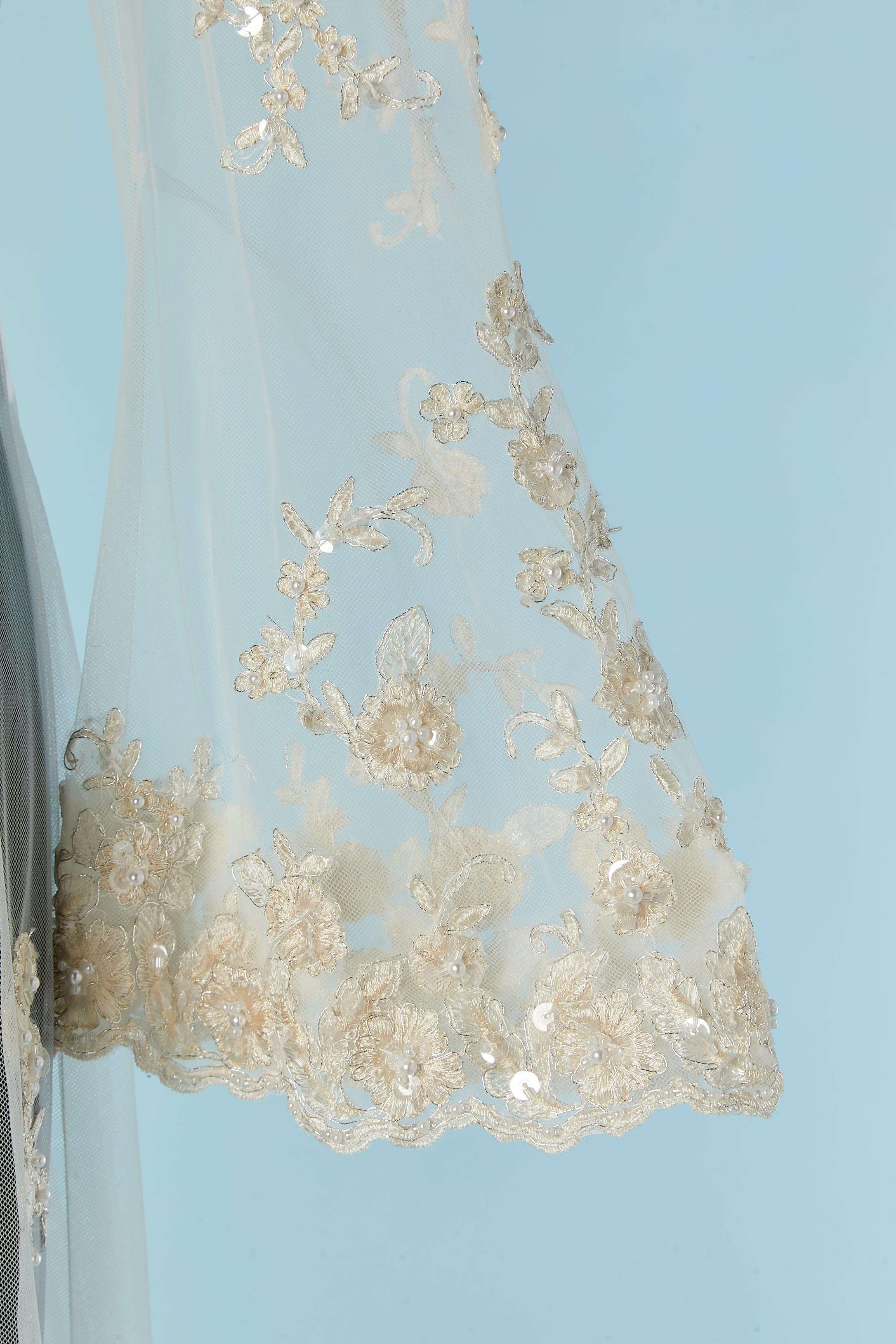 Ricami in pizzo bianco (paillettes trasparenti, filo bianco sporco e filo argento) e cappotto da sposa in tulle con strascico. Chiusura con gancio e occhiello al centro della parte anteriore. 
TAGLIA M 
