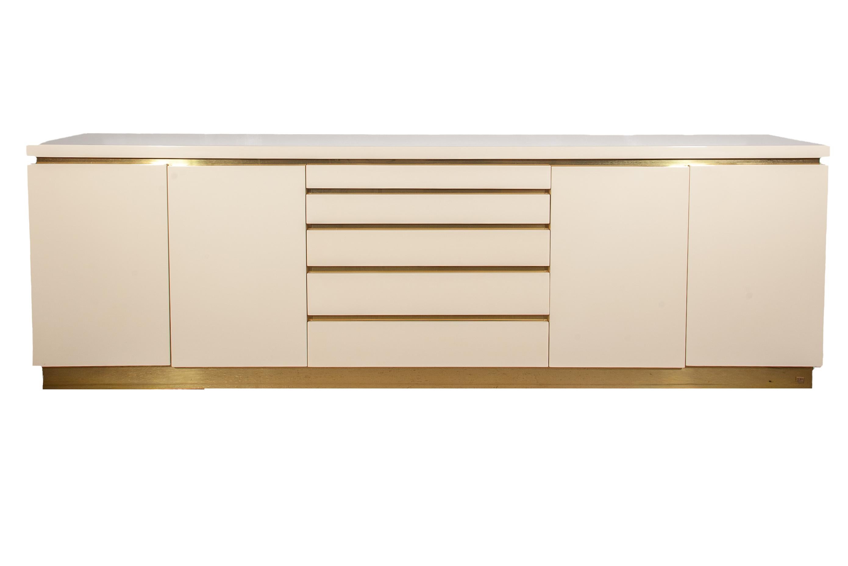 Splendida credenza in lacca bianca ed elementi in ottone progettata e realizzata a mano dal designer francese Jean Claude Mahey per Roche Bobois, 1980. I dettagli in ottone intorno ai cassetti, alle ante, alla base e al piano aggiungono un tocco di